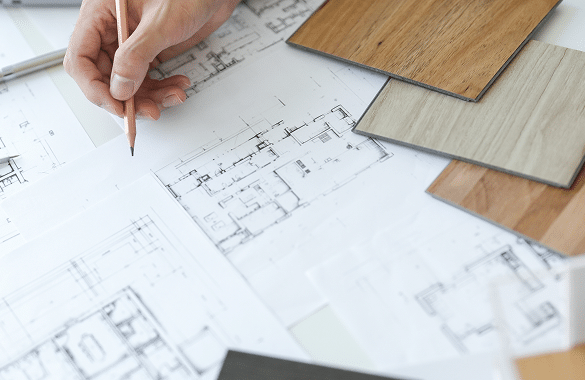 Hand marking up floor plans beside wood and laminate material samples
