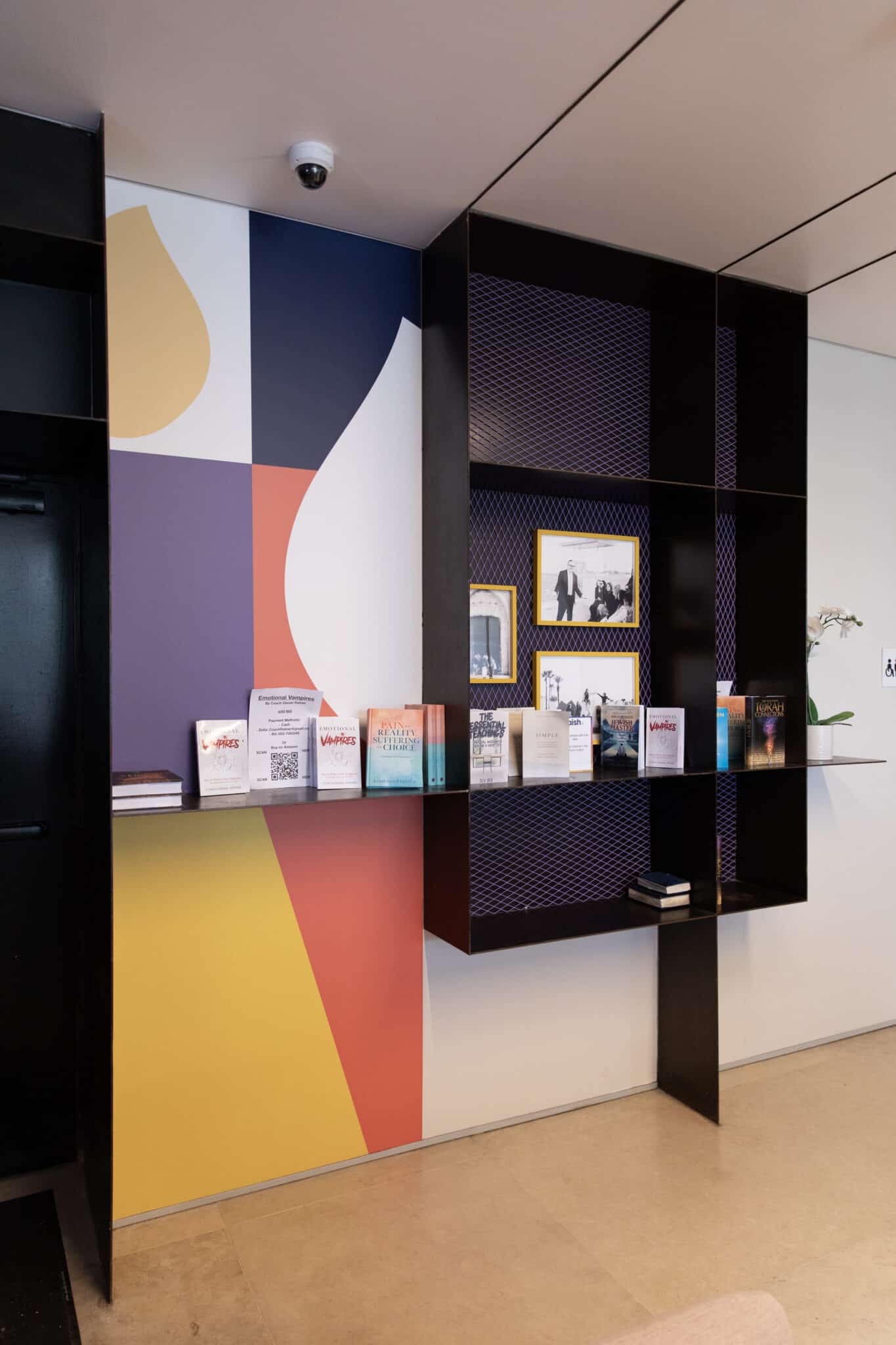Colourful abstract wall graphic beside a black display shelf