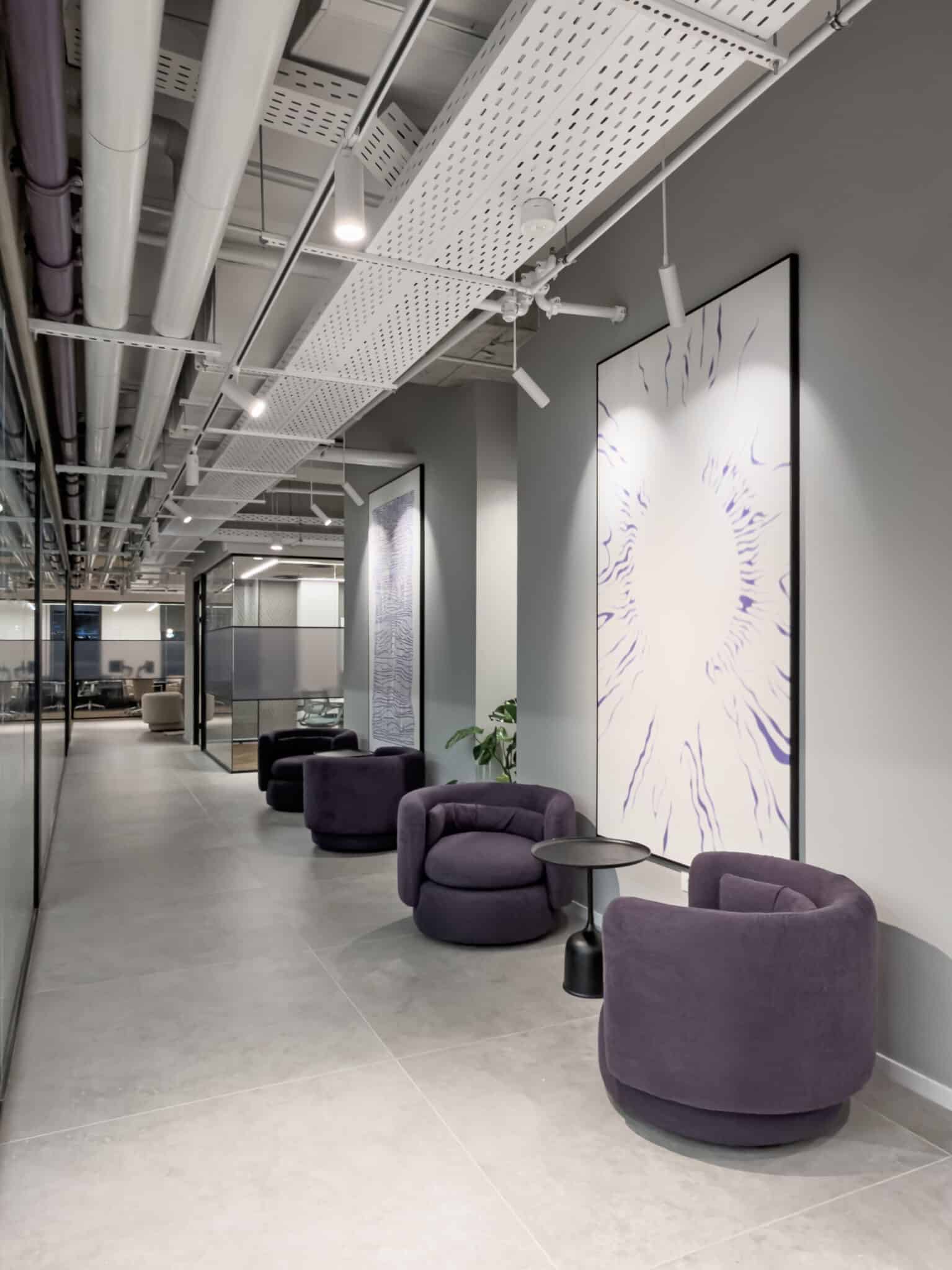 Framed artwork above purple armchairs in a corridor lounge