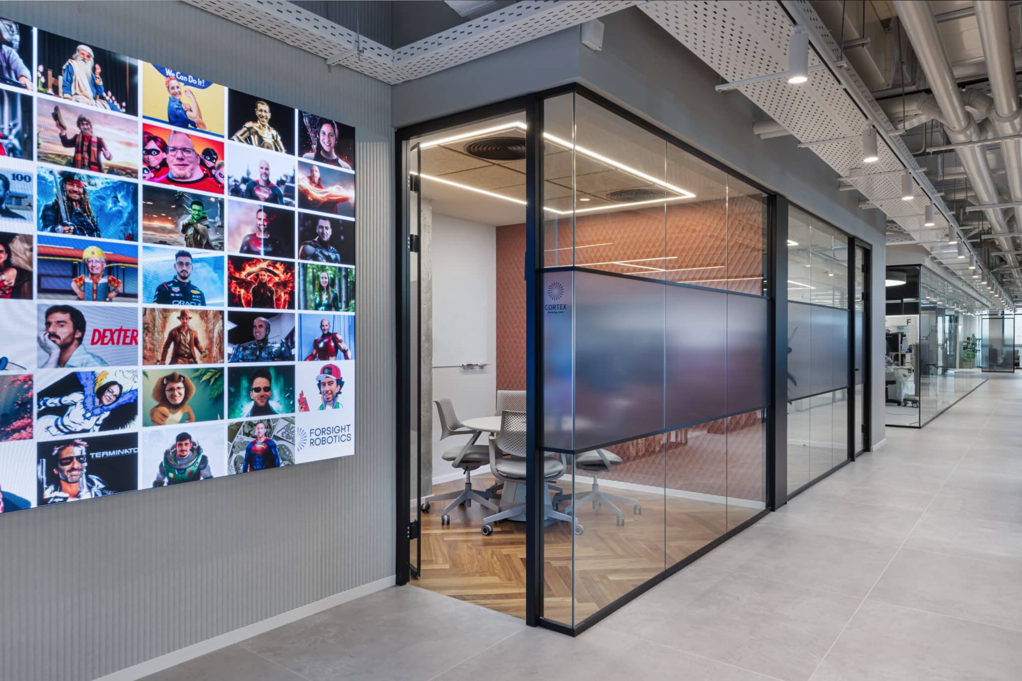 Team photo grid wall beside meeting room glass with a frosted band