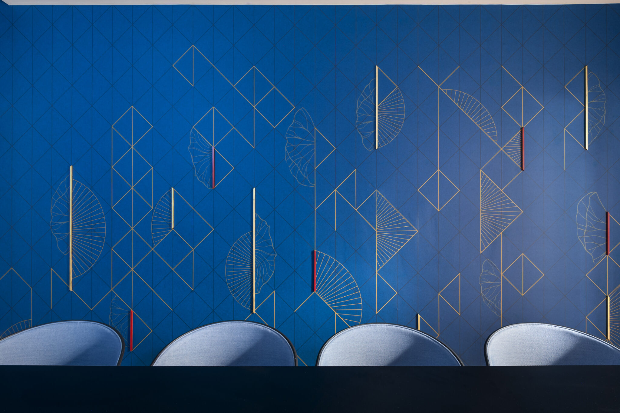 Gold and red geometric line graphic on a deep blue wall