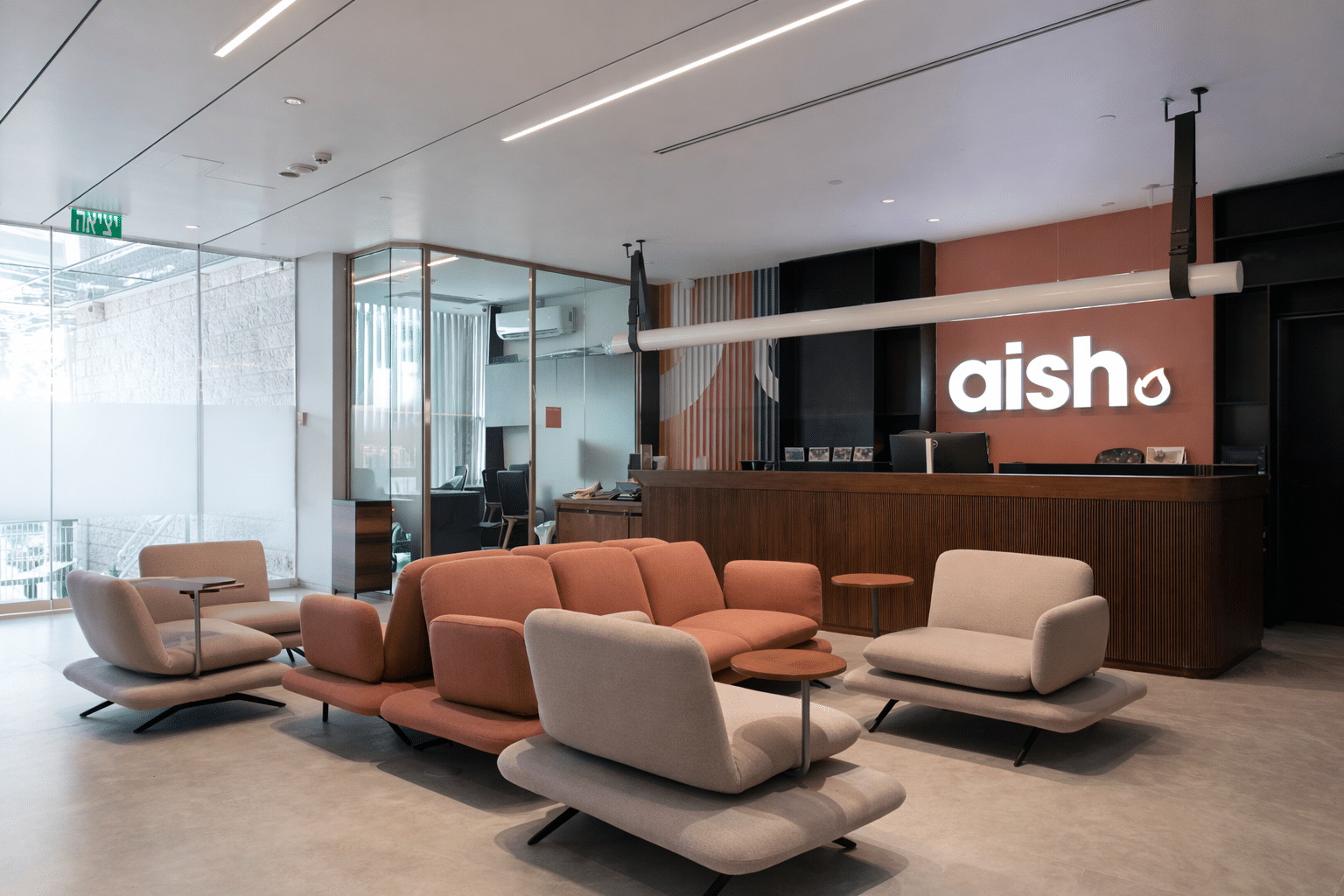 aish 3D logo on a terracotta wall above the reception desk
