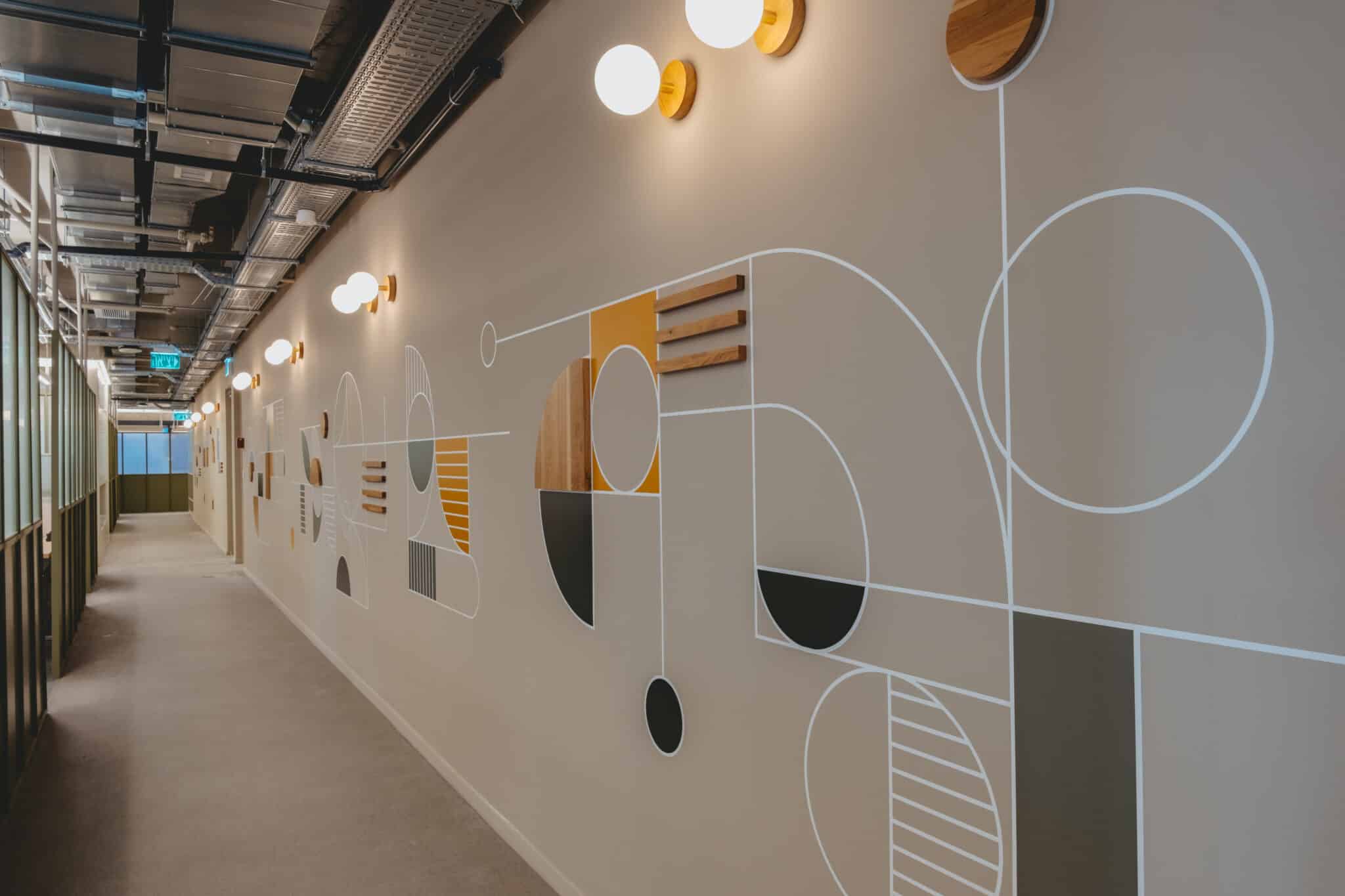 Geometric wall graphic with applied wood elements along a corridor