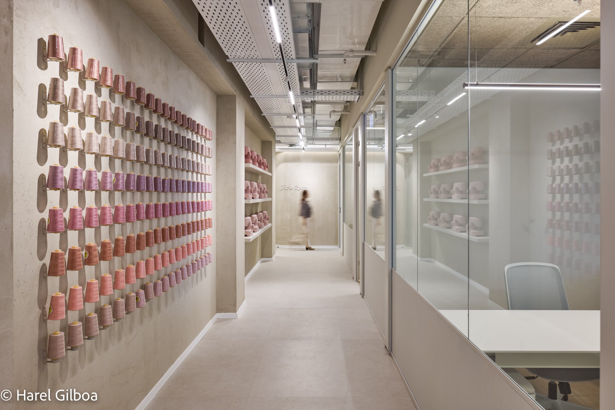 Wall display of thread spools in graded pink tones along a corridor
