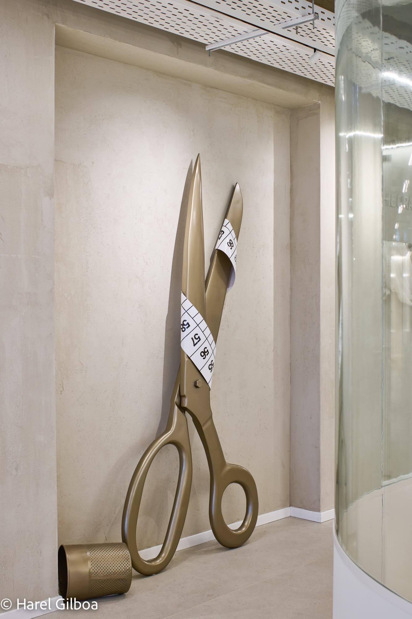 Giant scissors and tape measure sculpture in a wall niche