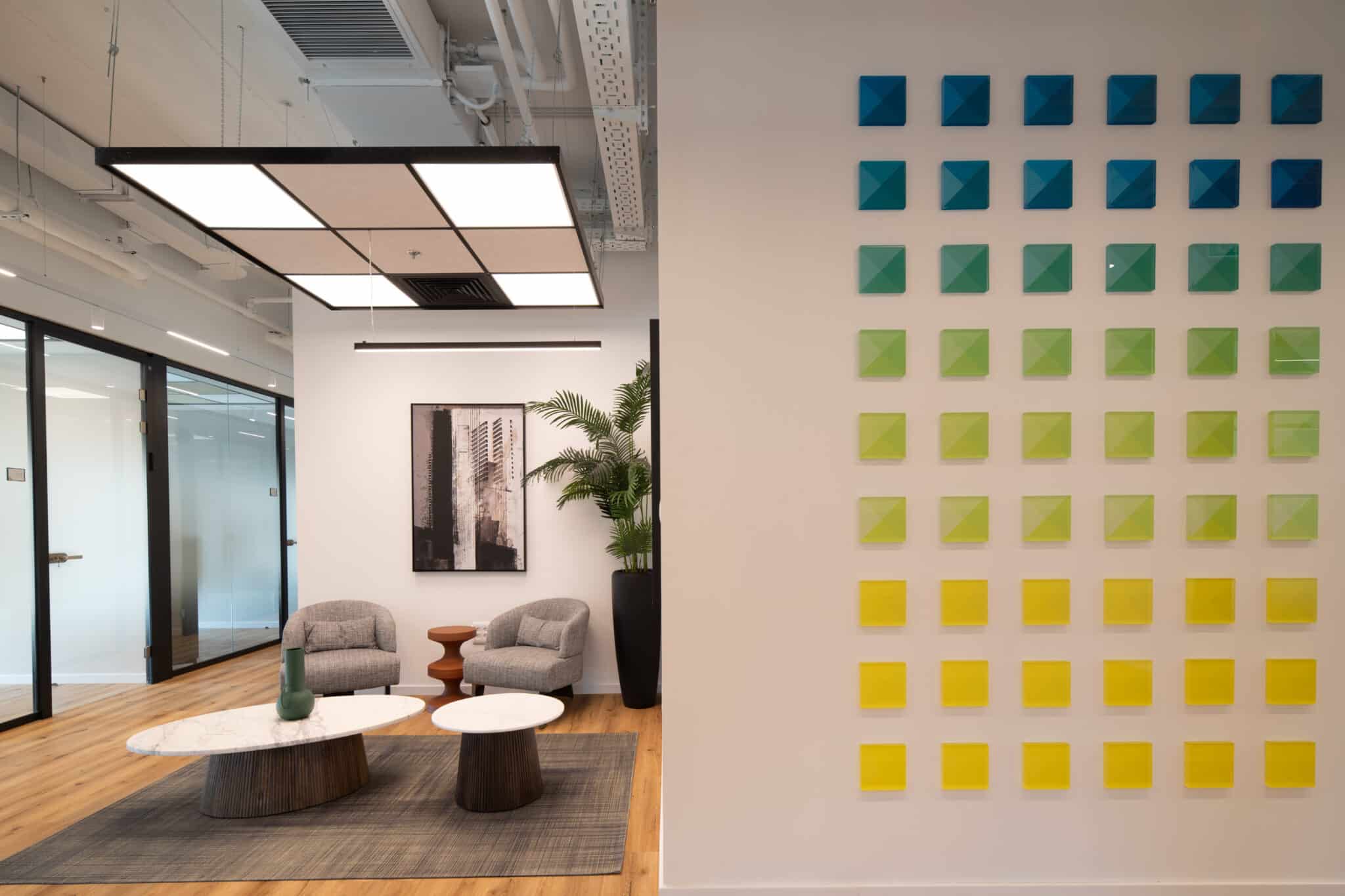 Wall of raised coloured tiles in a gradient beside a lounge