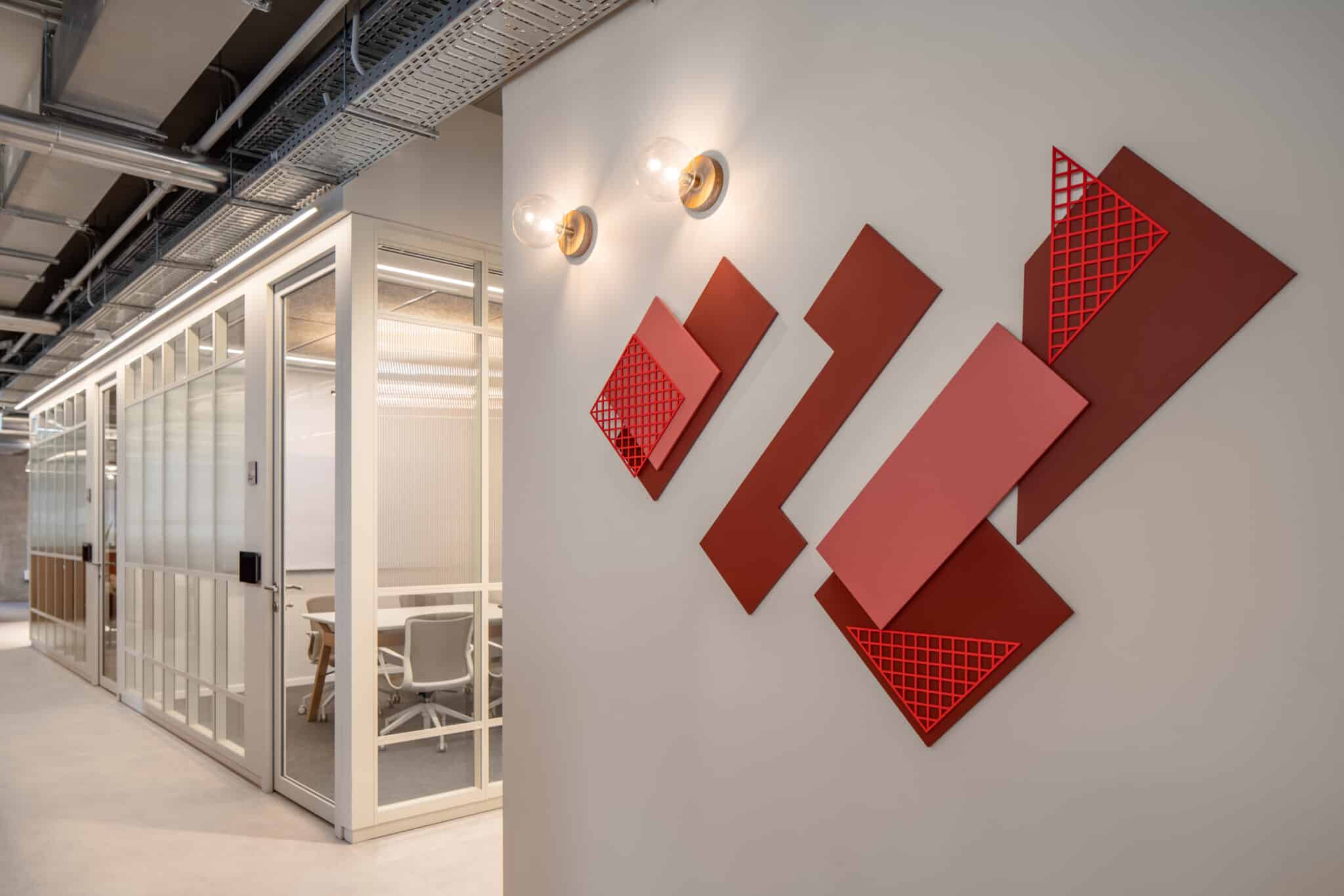 Angled red 3D wall panels with cut-out patterns in a corridor