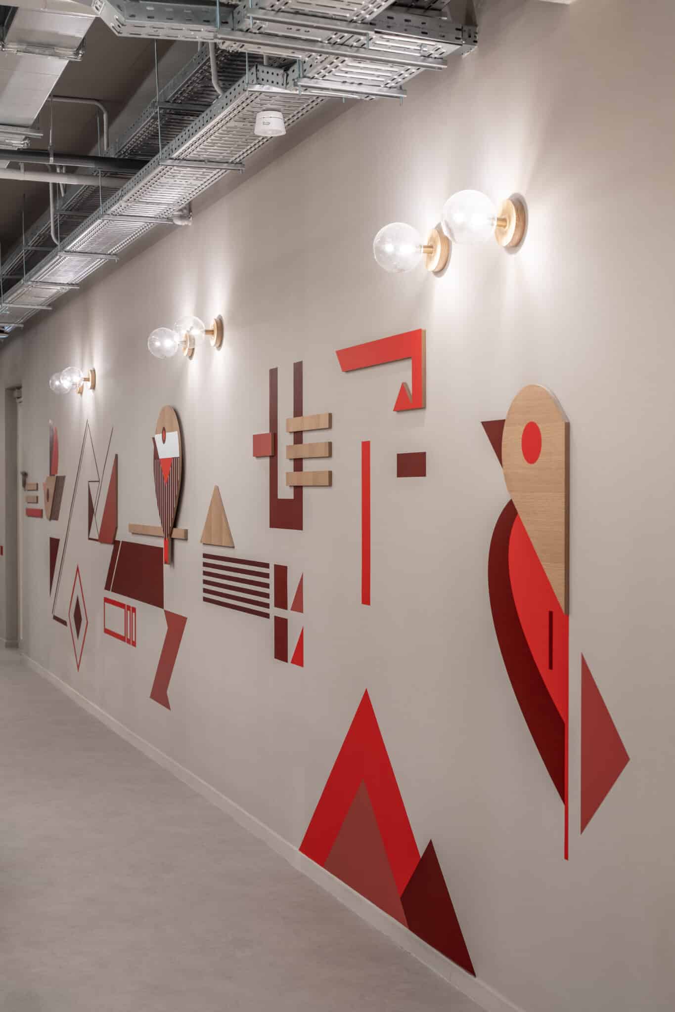 Geometric wall graphic in red with a bird shape along a corridor
