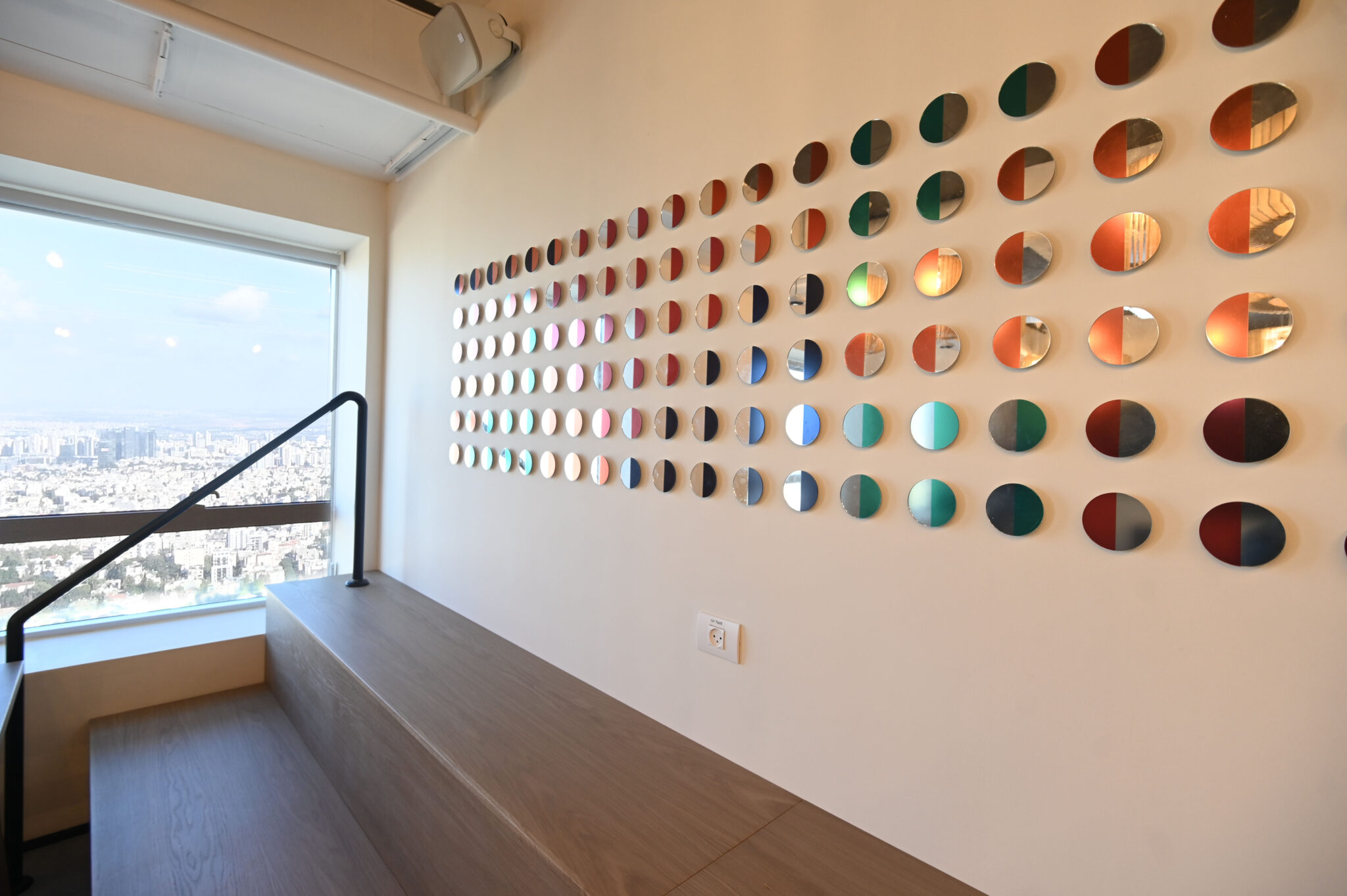Two tone coloured discs arranged in rows along a stair wall