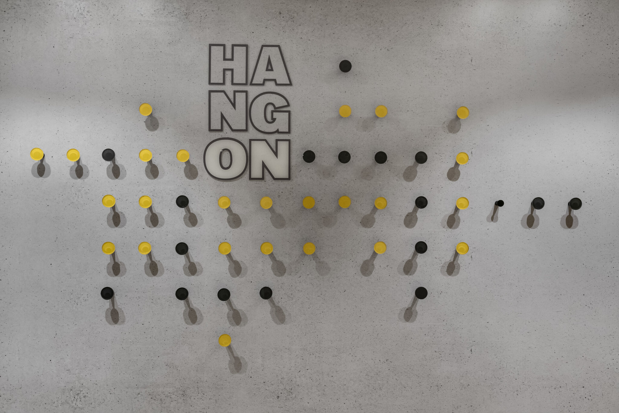 Coat hook wall with cut out letters on bare concrete