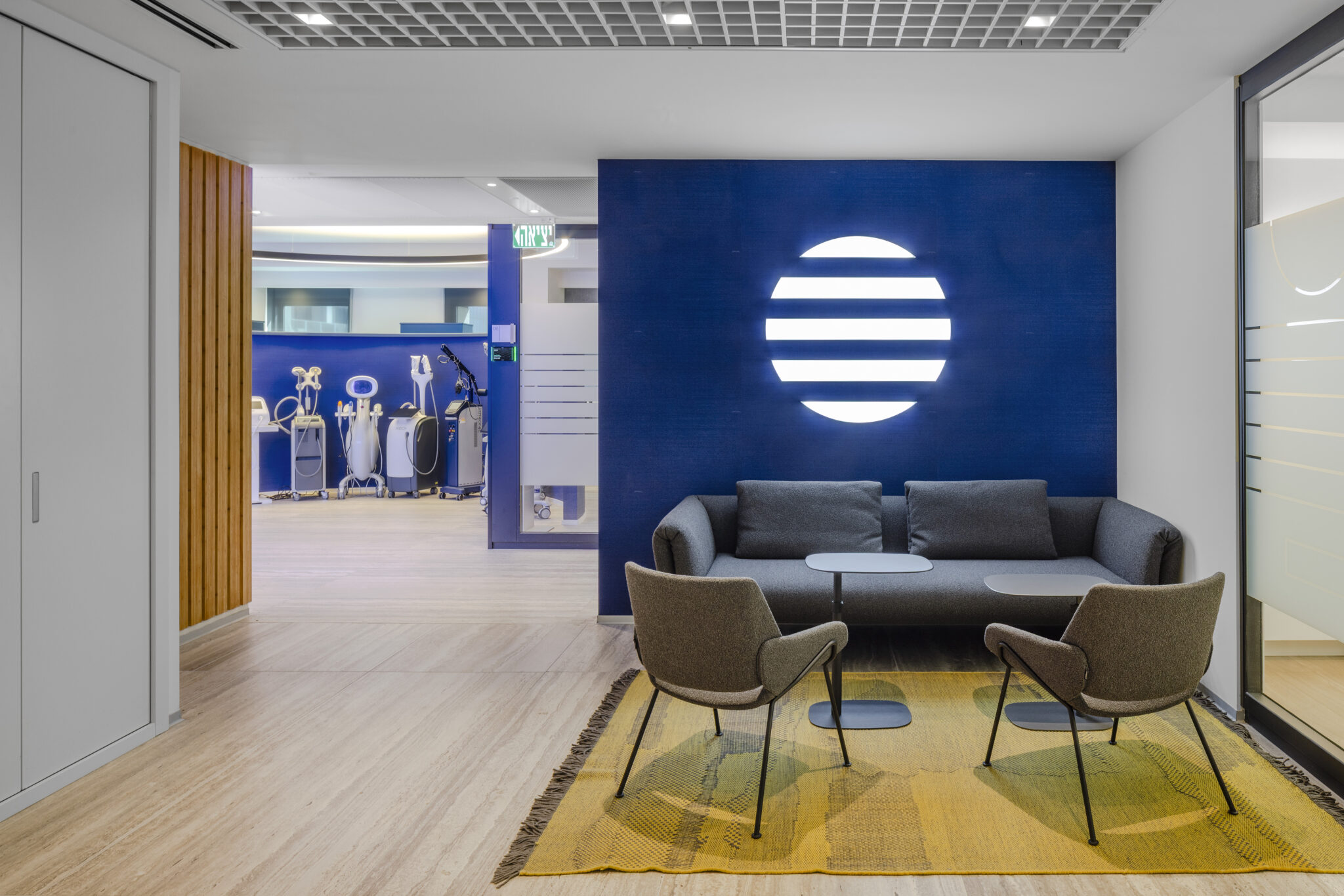 Illuminated round logo mark on a blue wall above a sofa