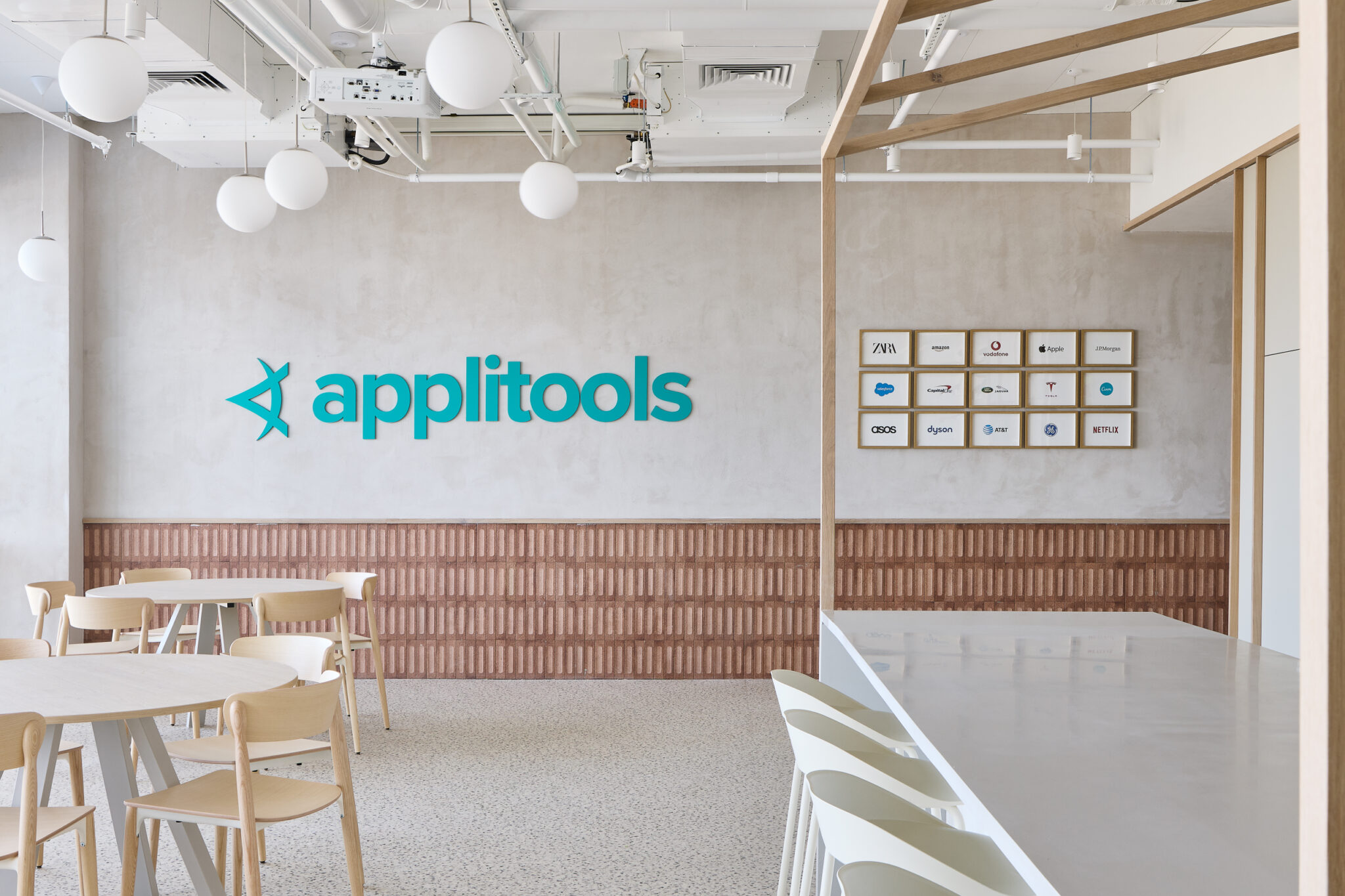 applitools 3D logo and framed client logos on a concrete wall