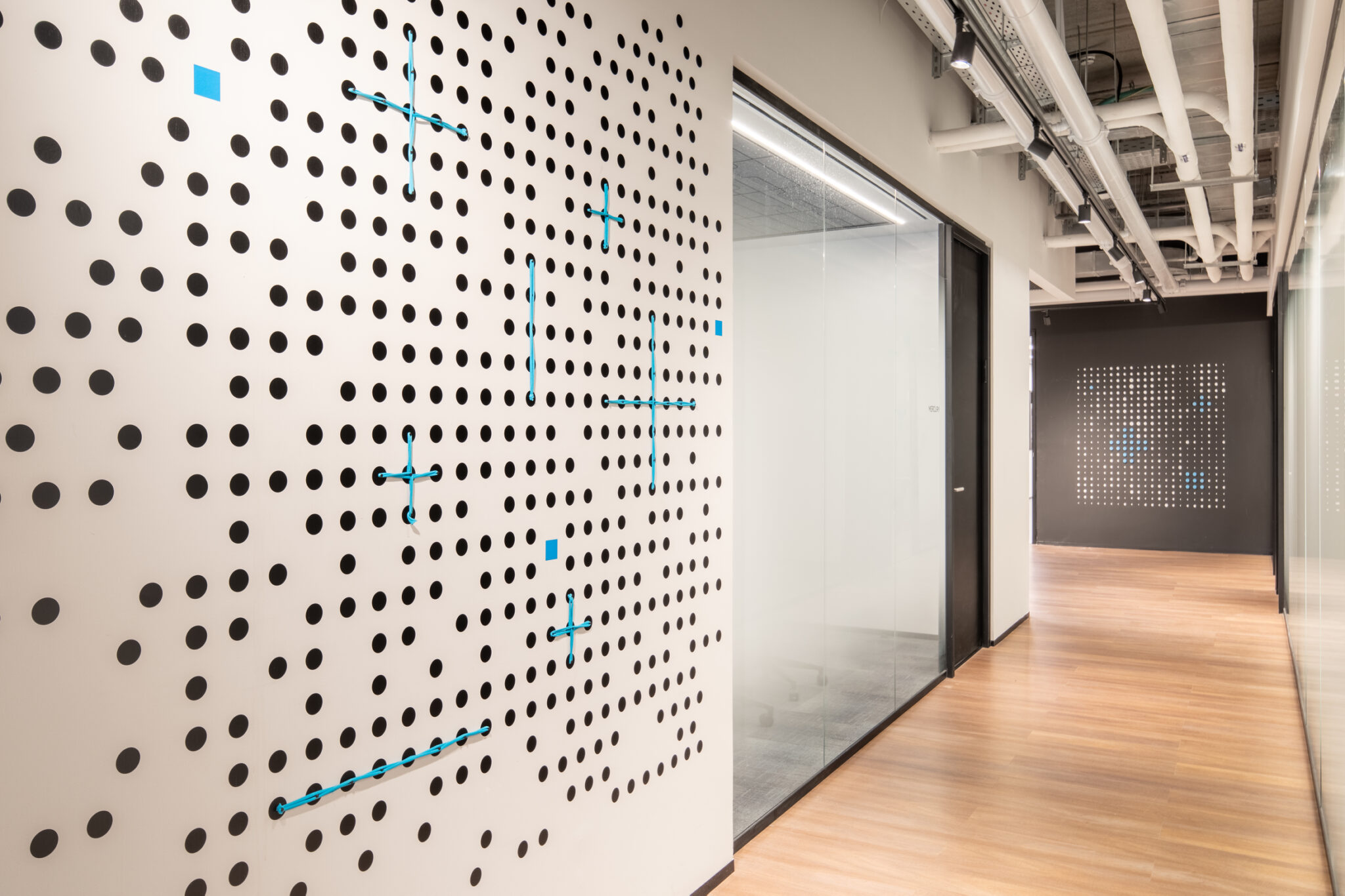 Black dot pattern wall graphic with blue crosses along a corridor