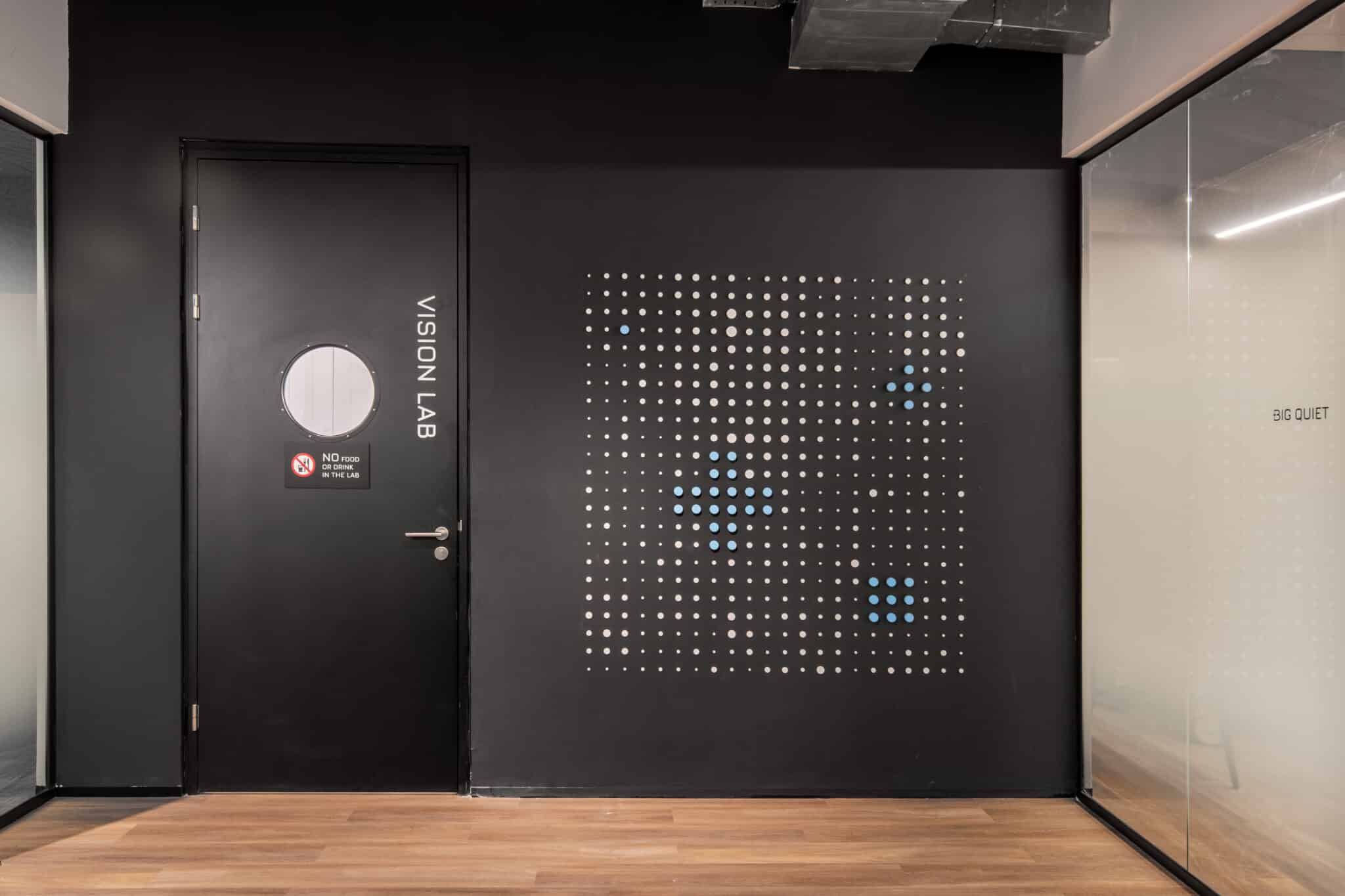VISION LAB letters on the door next to a dot pattern on a black wall