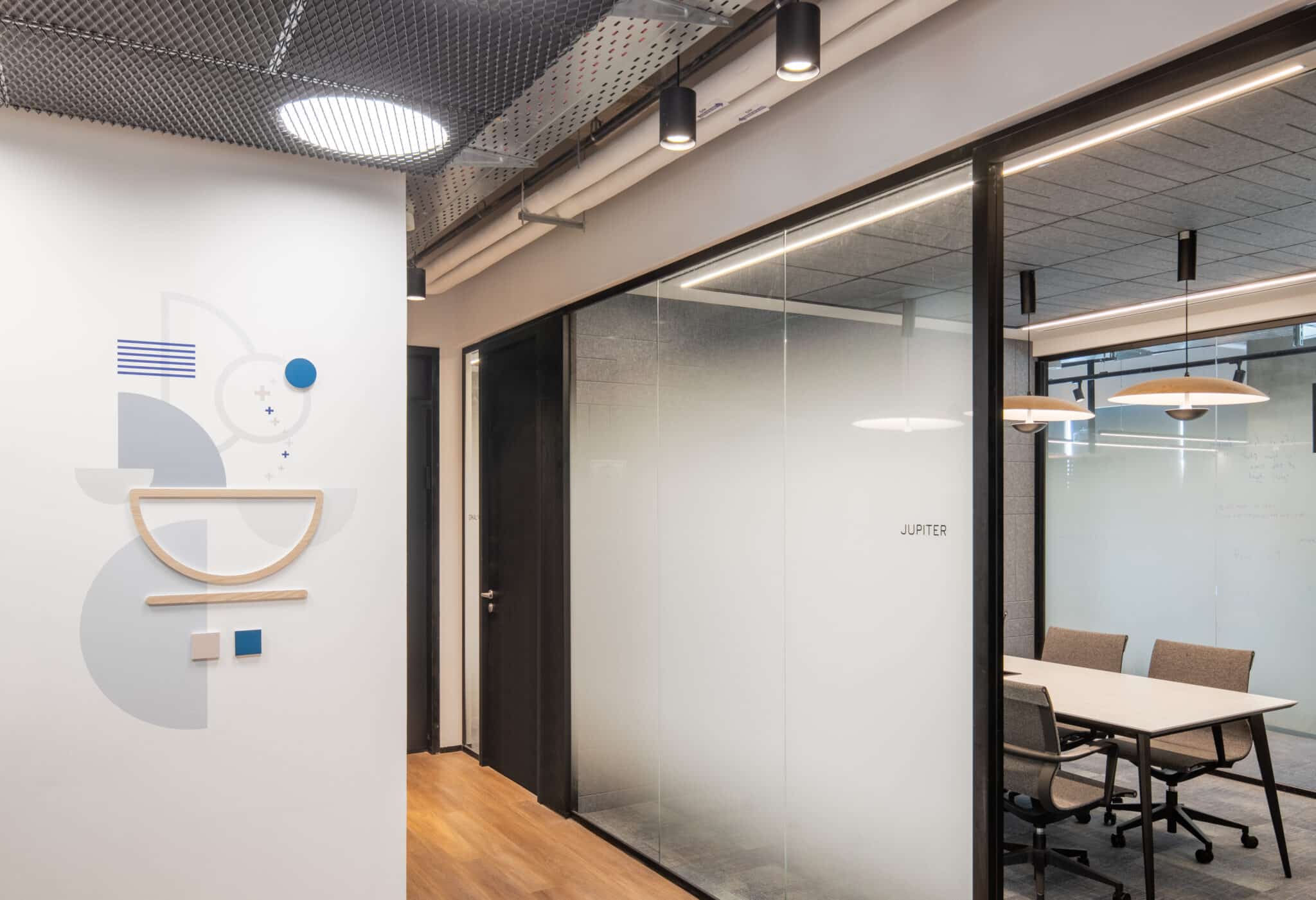 Geometric wall graphic with a wood arc shelf and JUPITER on the glass