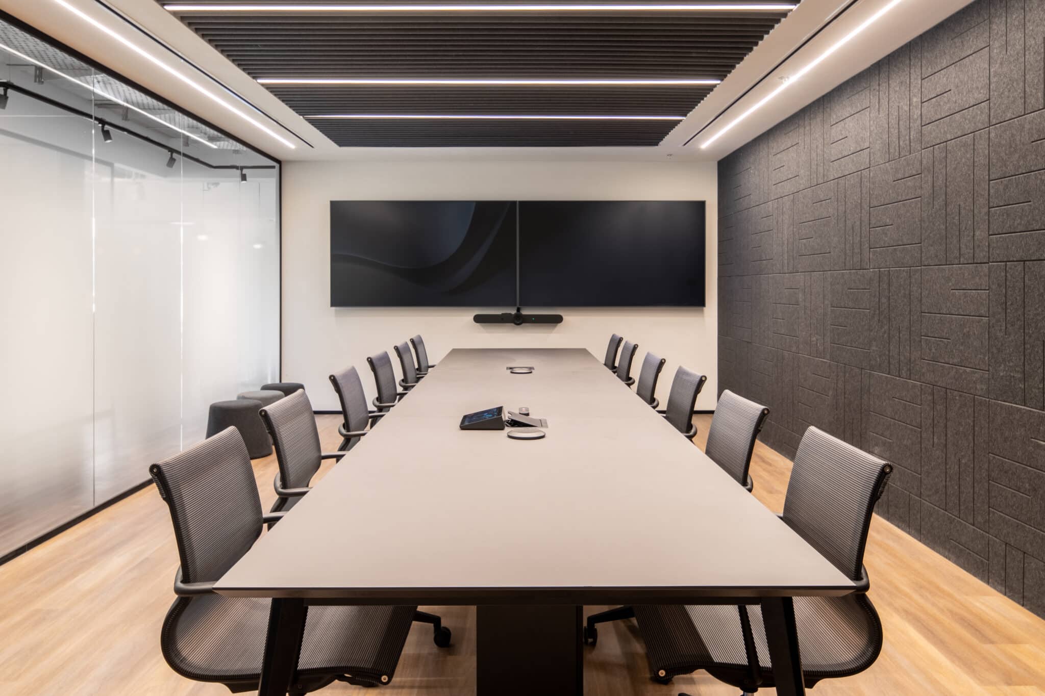 Dark textured acoustic wall panels in a meeting room with two screens