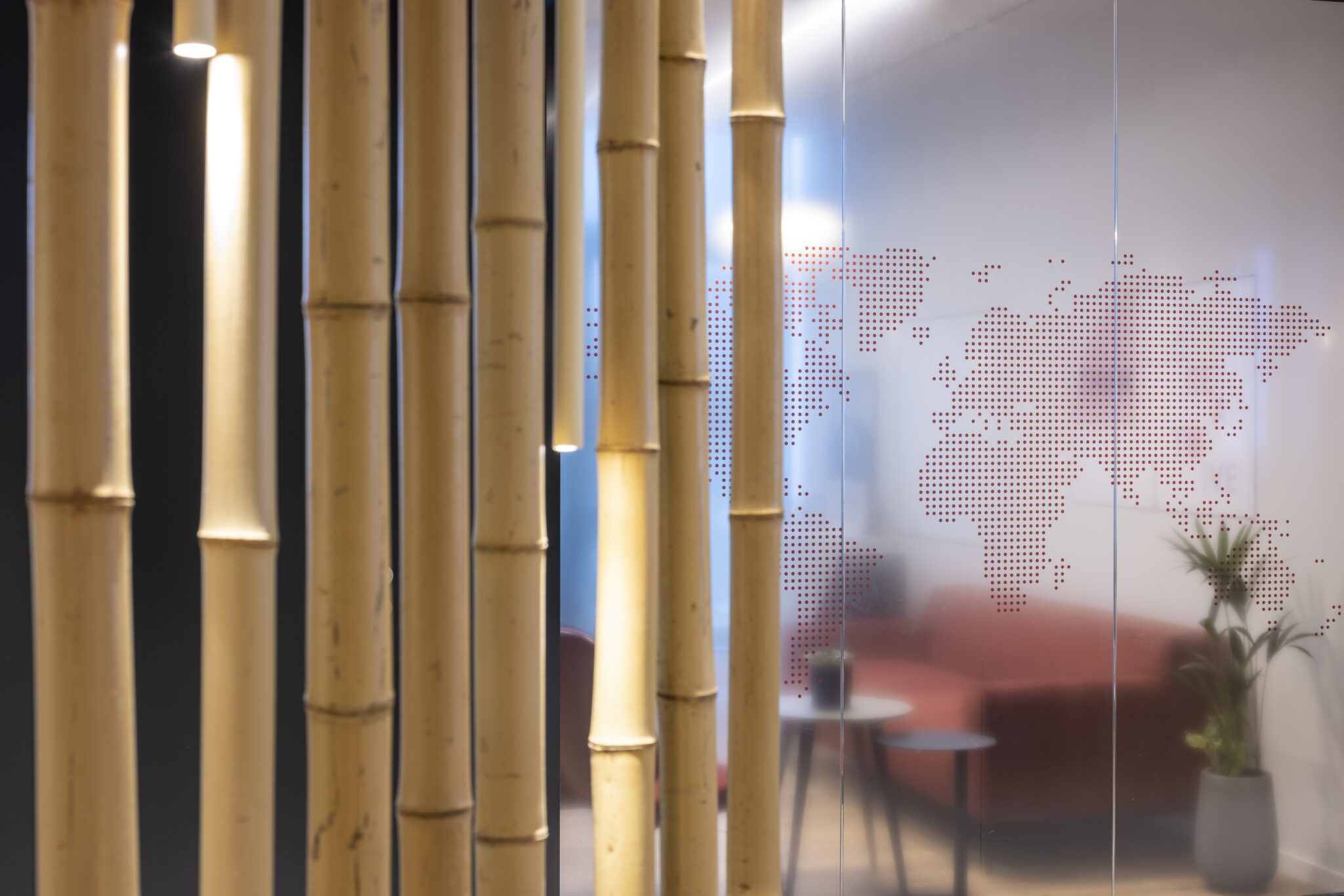 Dotted world map graphic on frosted glass behind bamboo poles