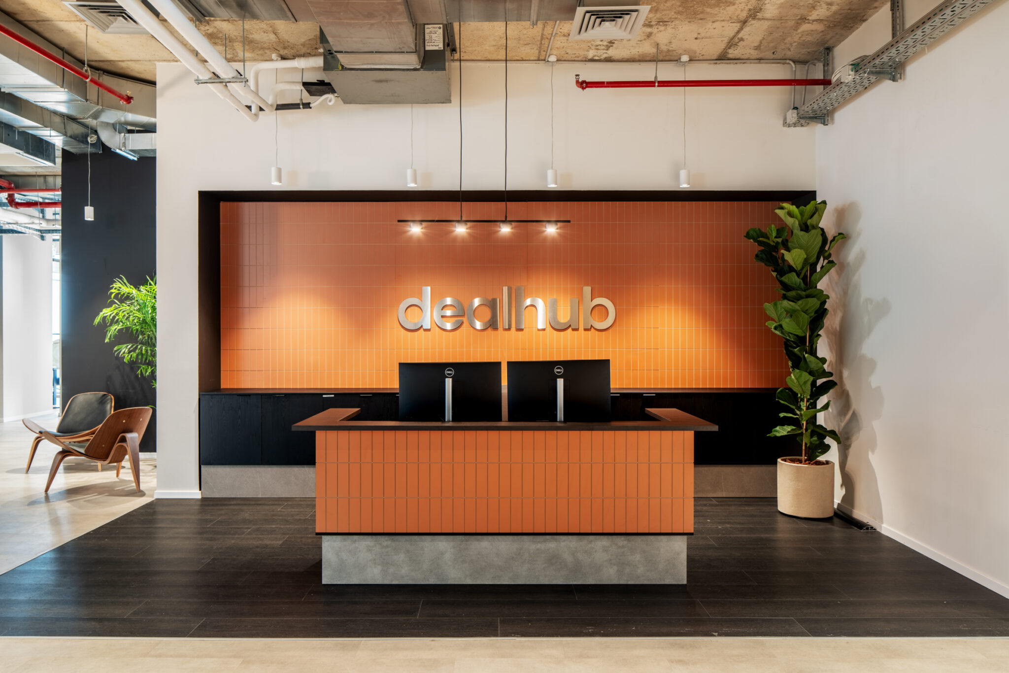 dealhub 3D logo on a tiled reception wall above the desk