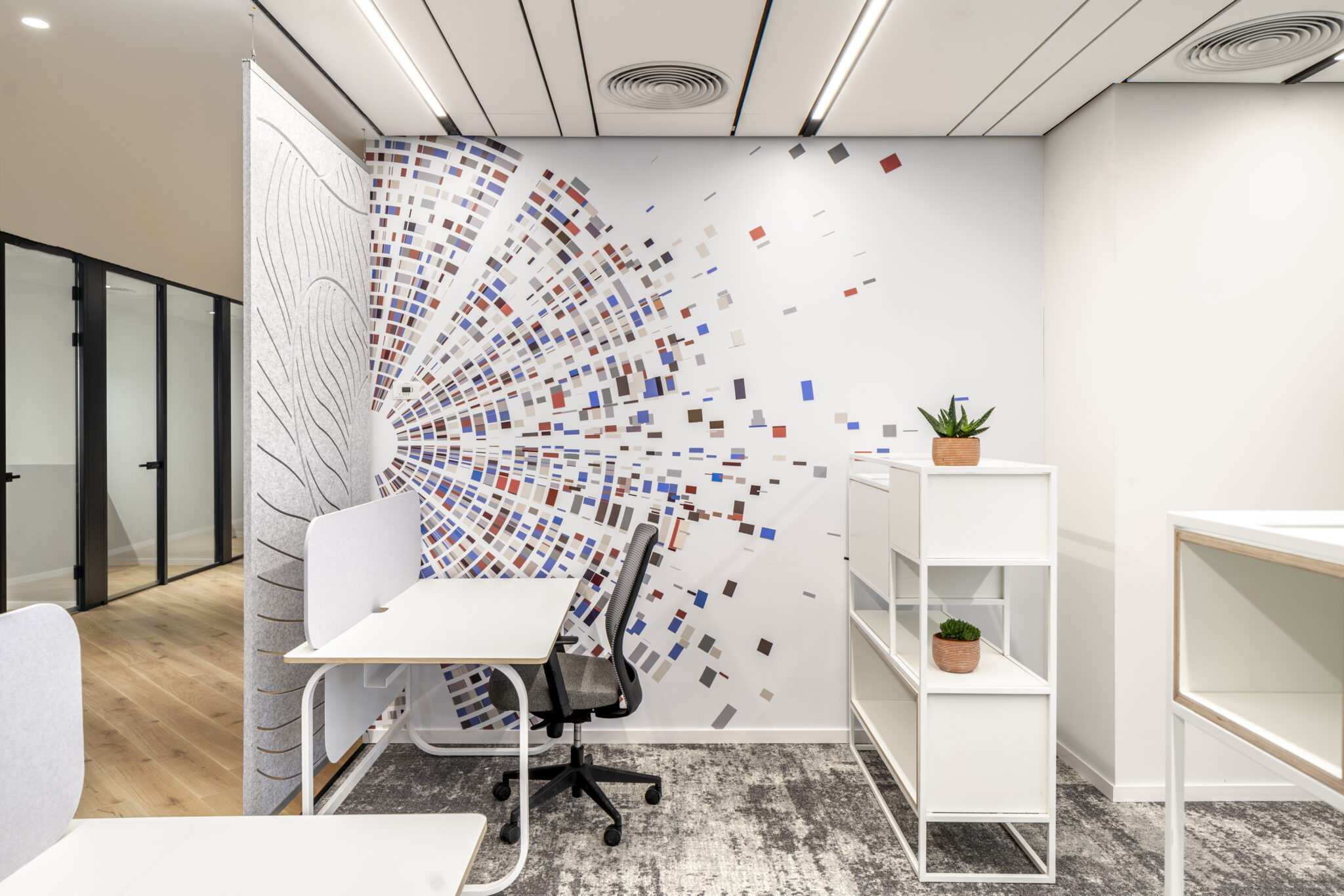 Wall graphic of scattered squares beside a carved acoustic felt panel