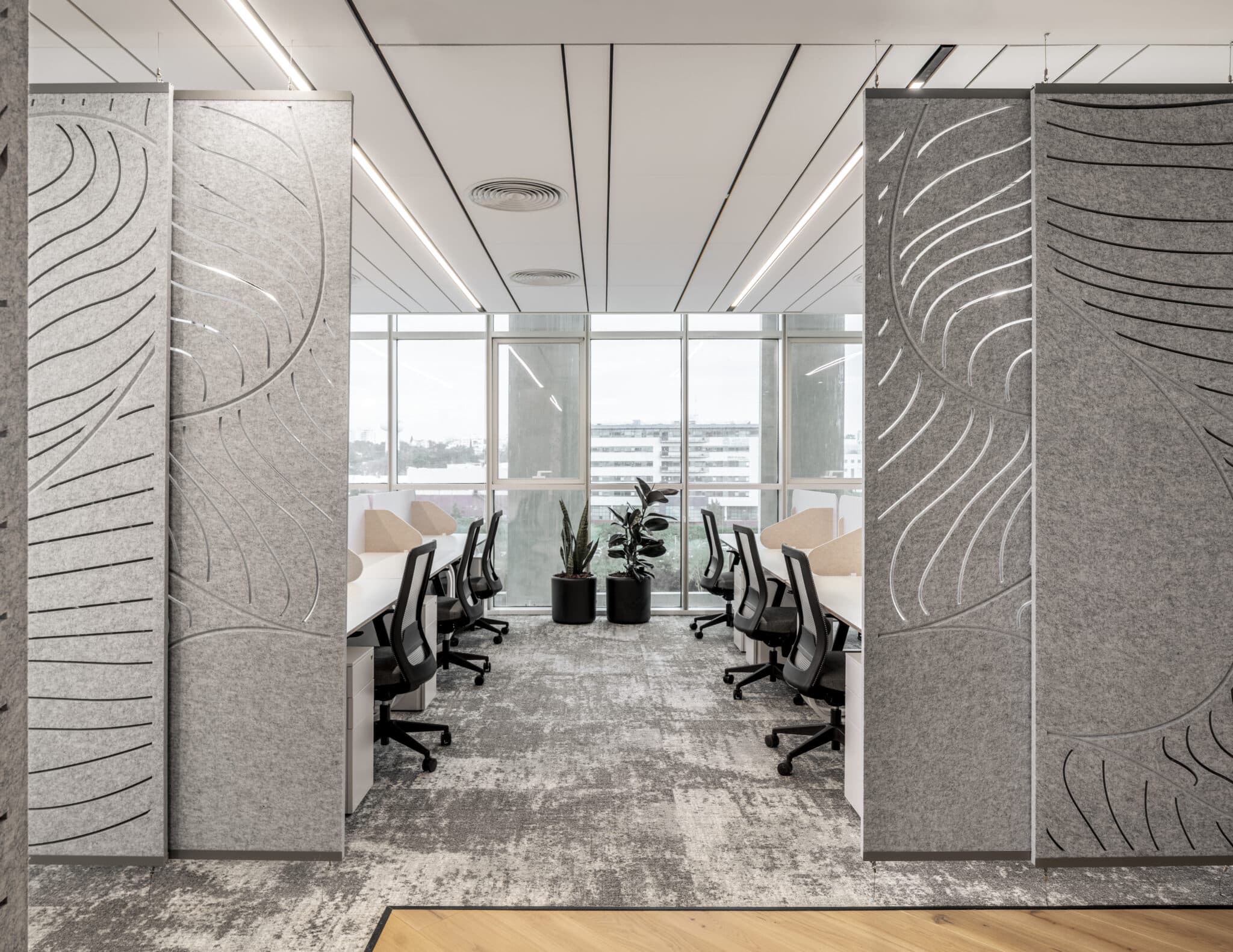 Carved acoustic felt screens with leaf pattern between office desks