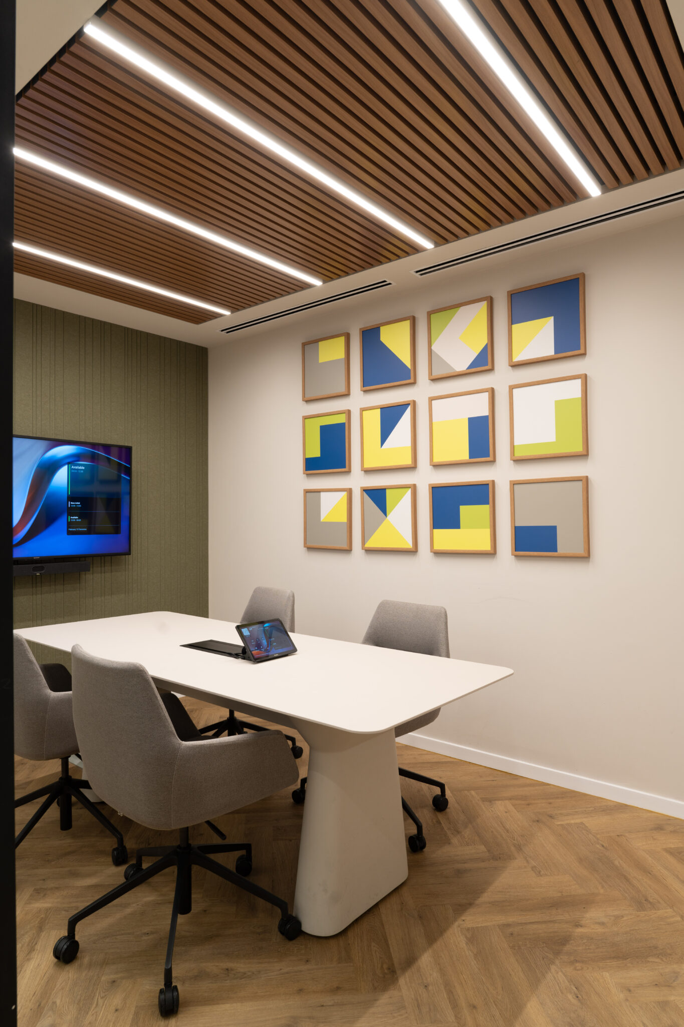 Twelve framed geometric prints in a grid on a meeting room wall