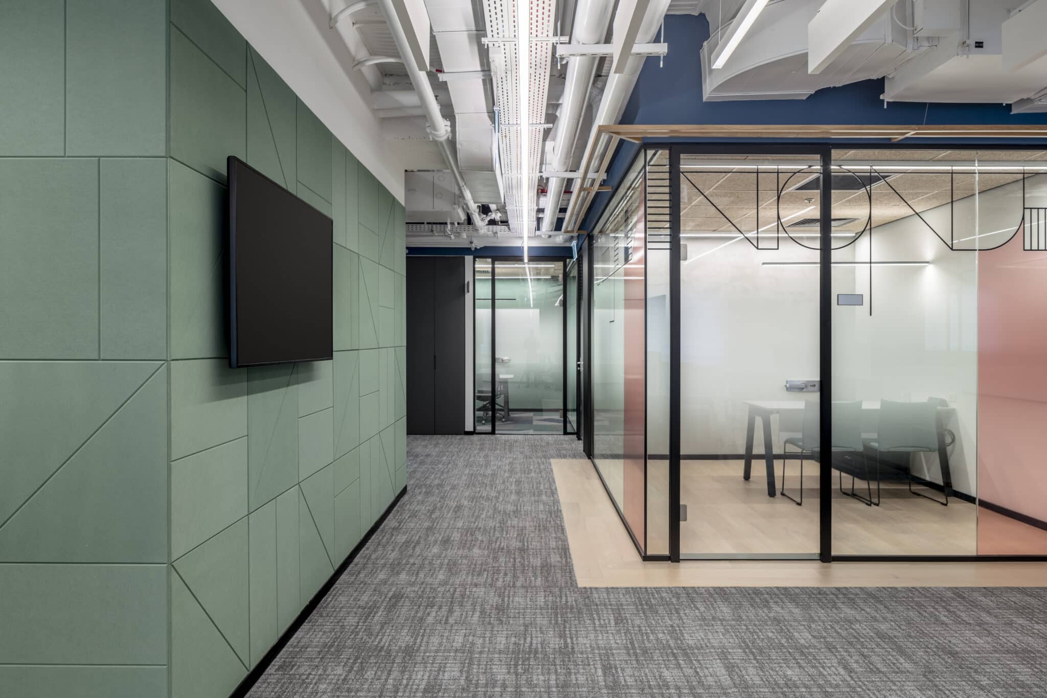 Green routed panel wall beside glass with line graphics