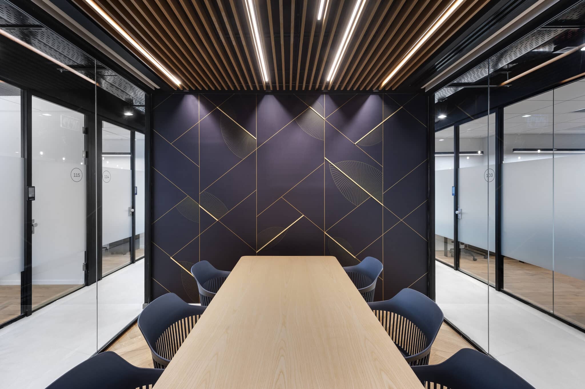 Gold geometric line graphic across a purple meeting room wall
