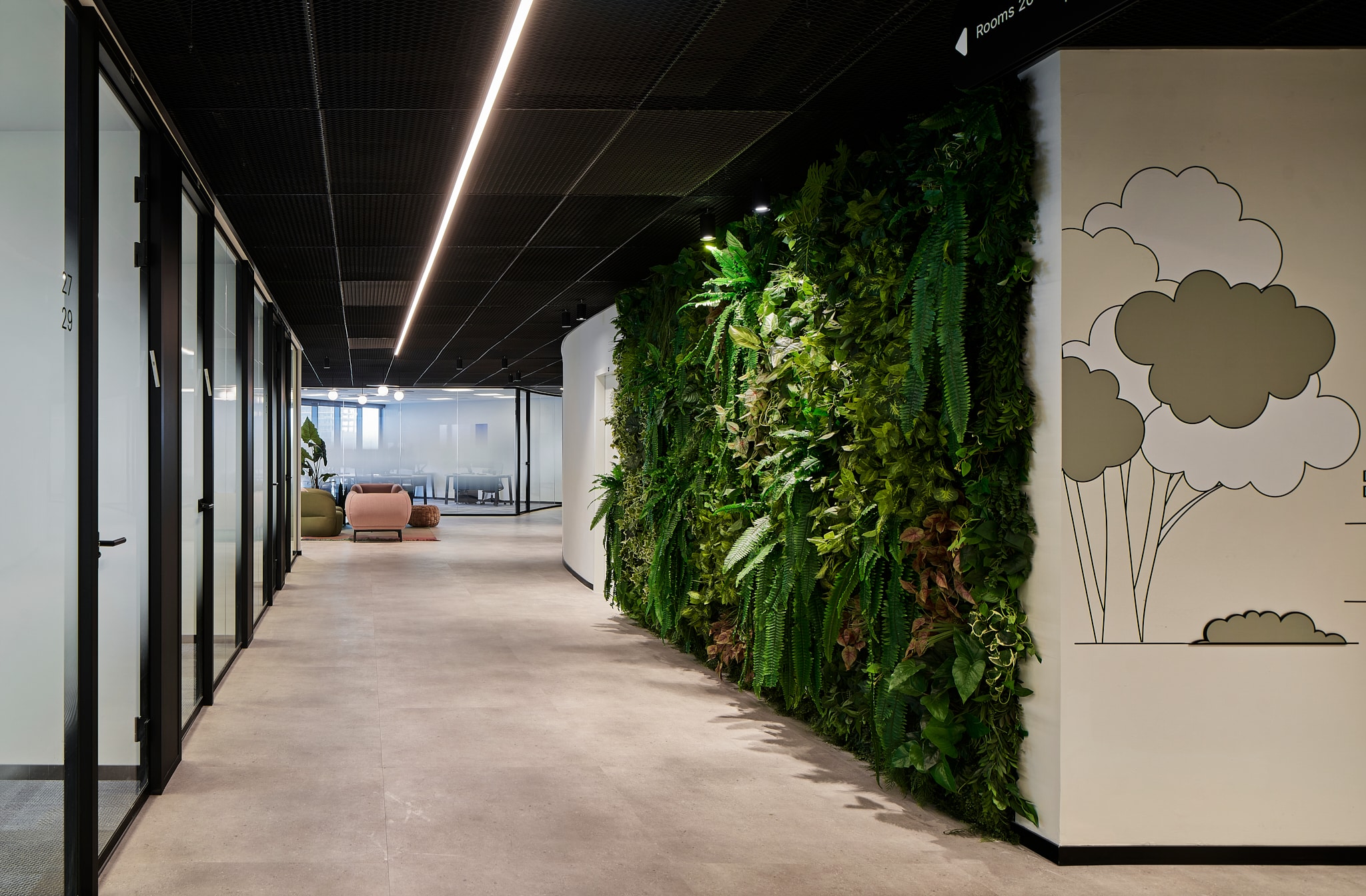 Line drawing wall graphic of clouds and trees beside a plant wall