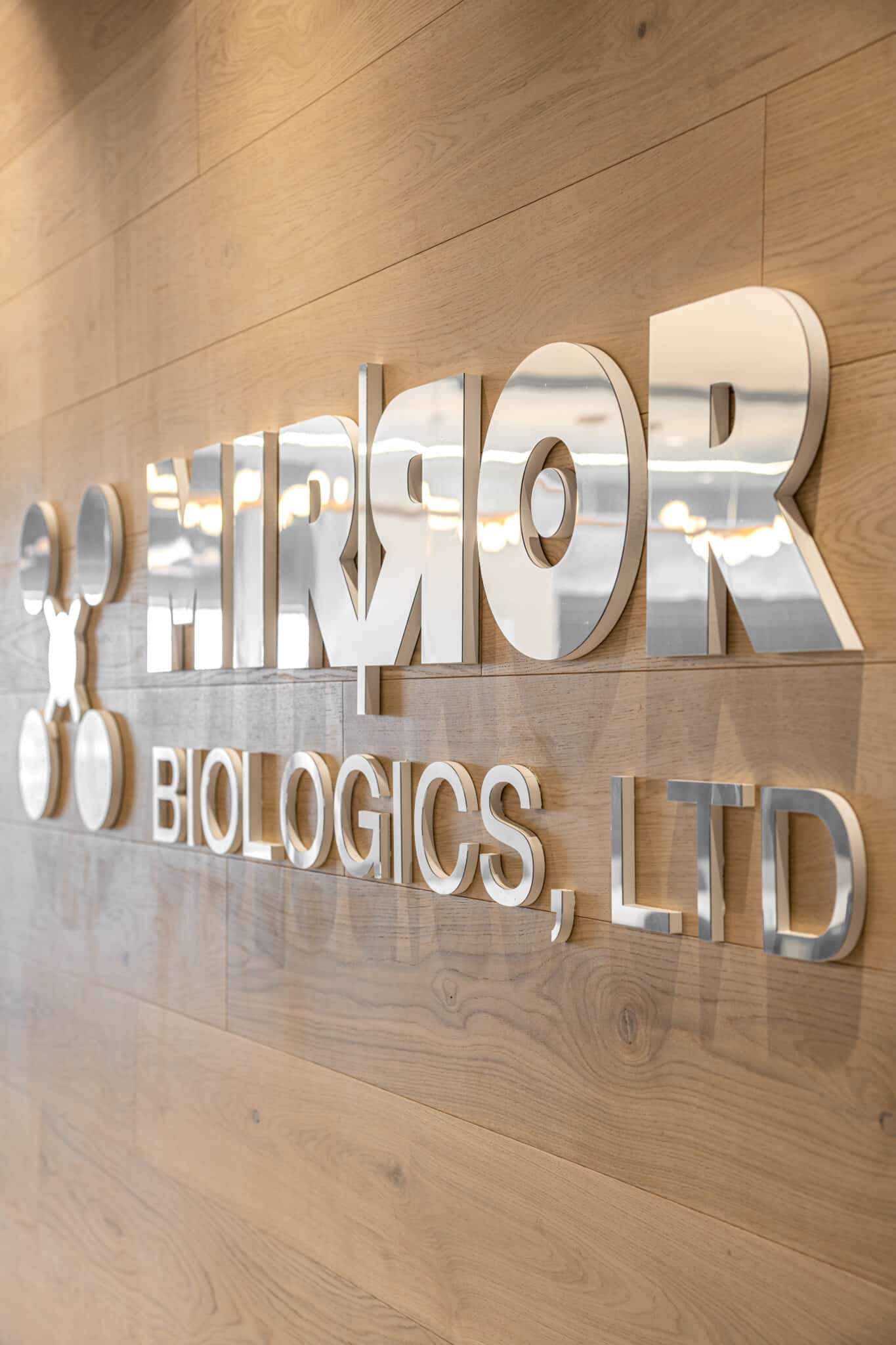 Close-up of the brushed metal Mirror Biologics letters on wood