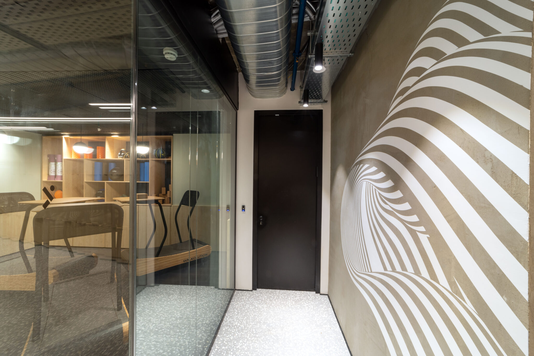 White striped swirl wall graphic on a concrete corridor wall