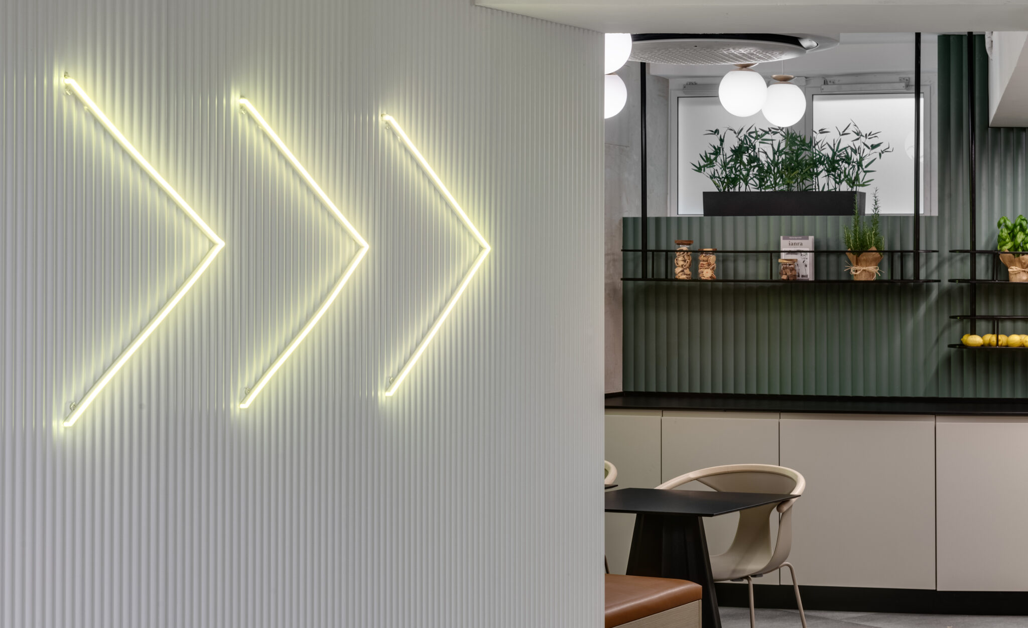 Three neon arrows as lit elements on a fluted white wall