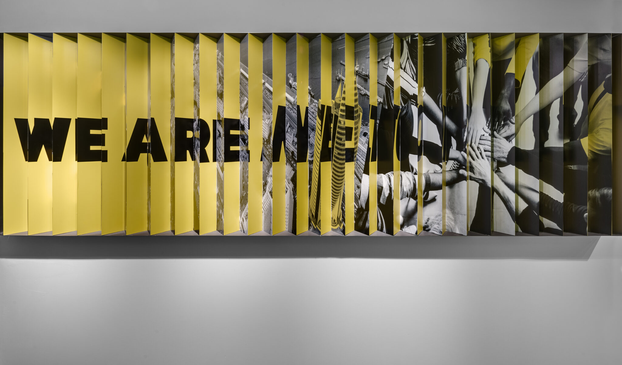 Angled slat wall showing lettering on one side and a photo on the other