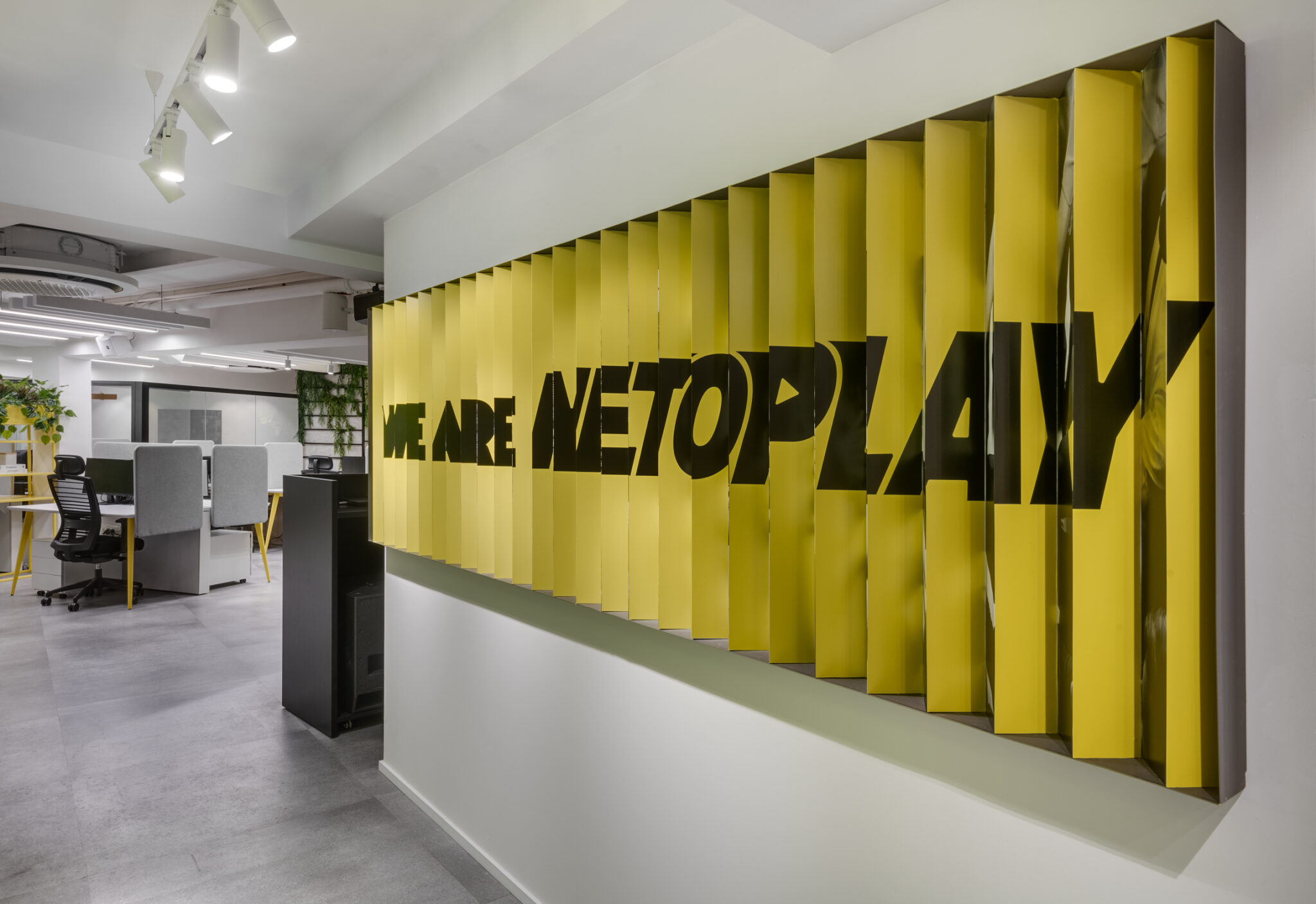 WE ARE NETOPLAY sign built from yellow angled slats