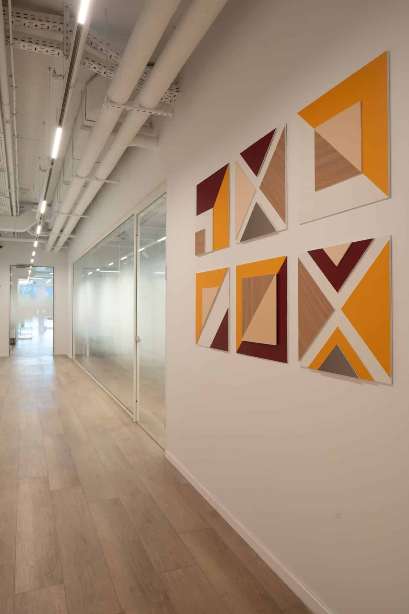 Four framed geometric artworks on a corridor wall