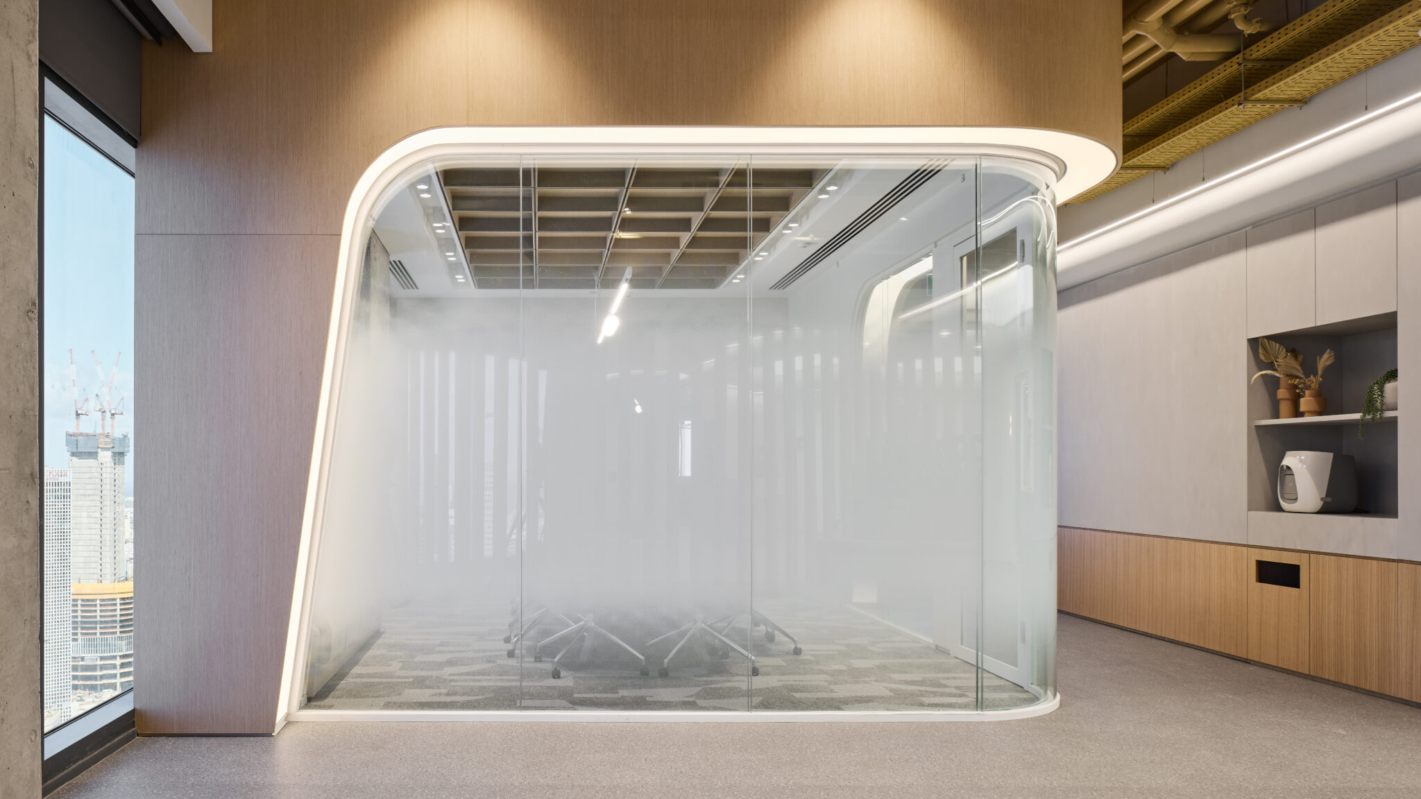 Curved glass meeting pod with a lit outline in an office