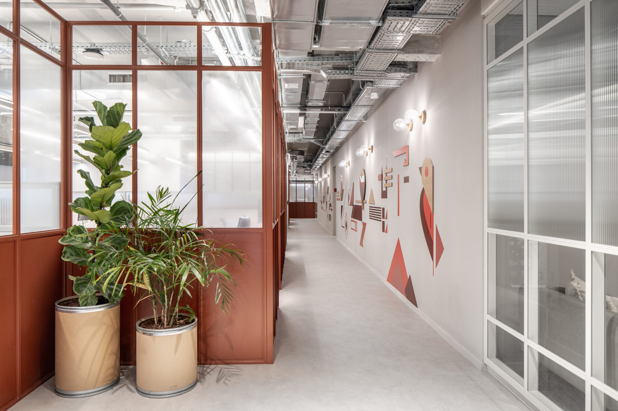 Geometric red wall graphic along a corridor with fluted glass