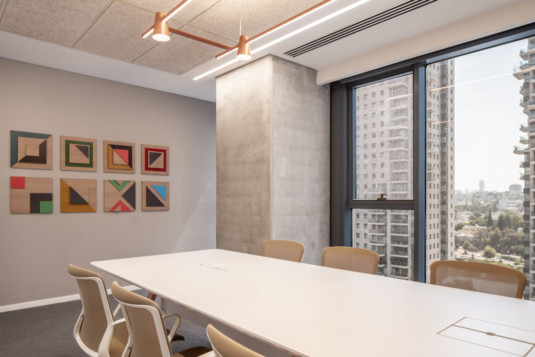 Grid of framed geometric artworks in a meeting room