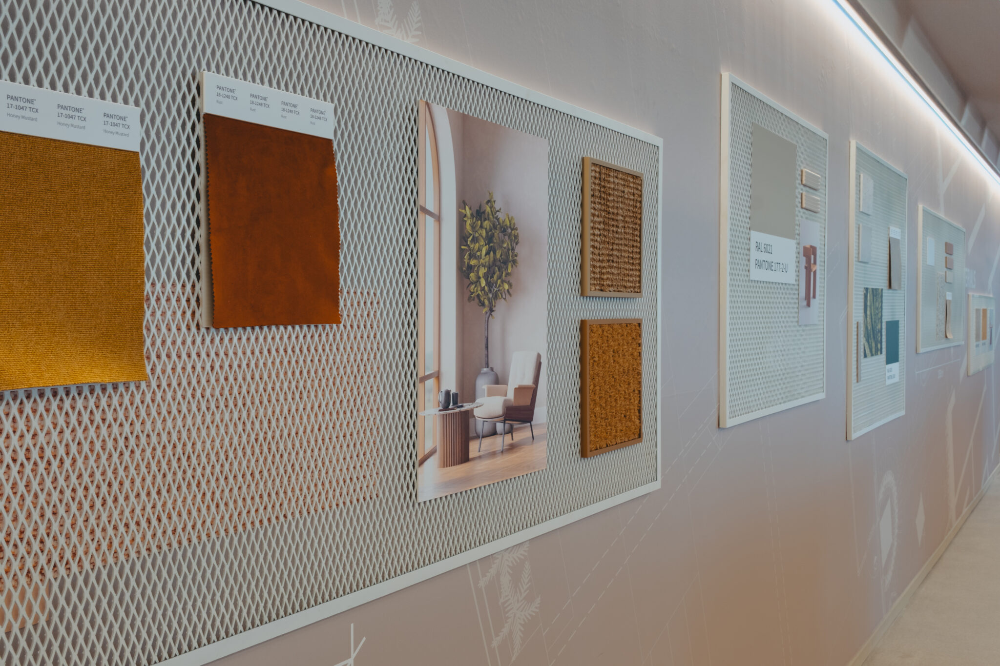Material sample boards on a mesh panel wall in a corridor