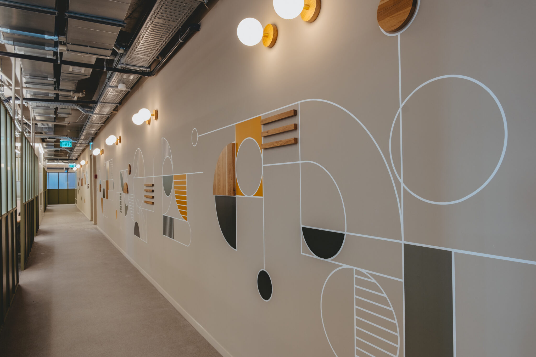 Long geometric wall graphic with wood discs down a corridor
