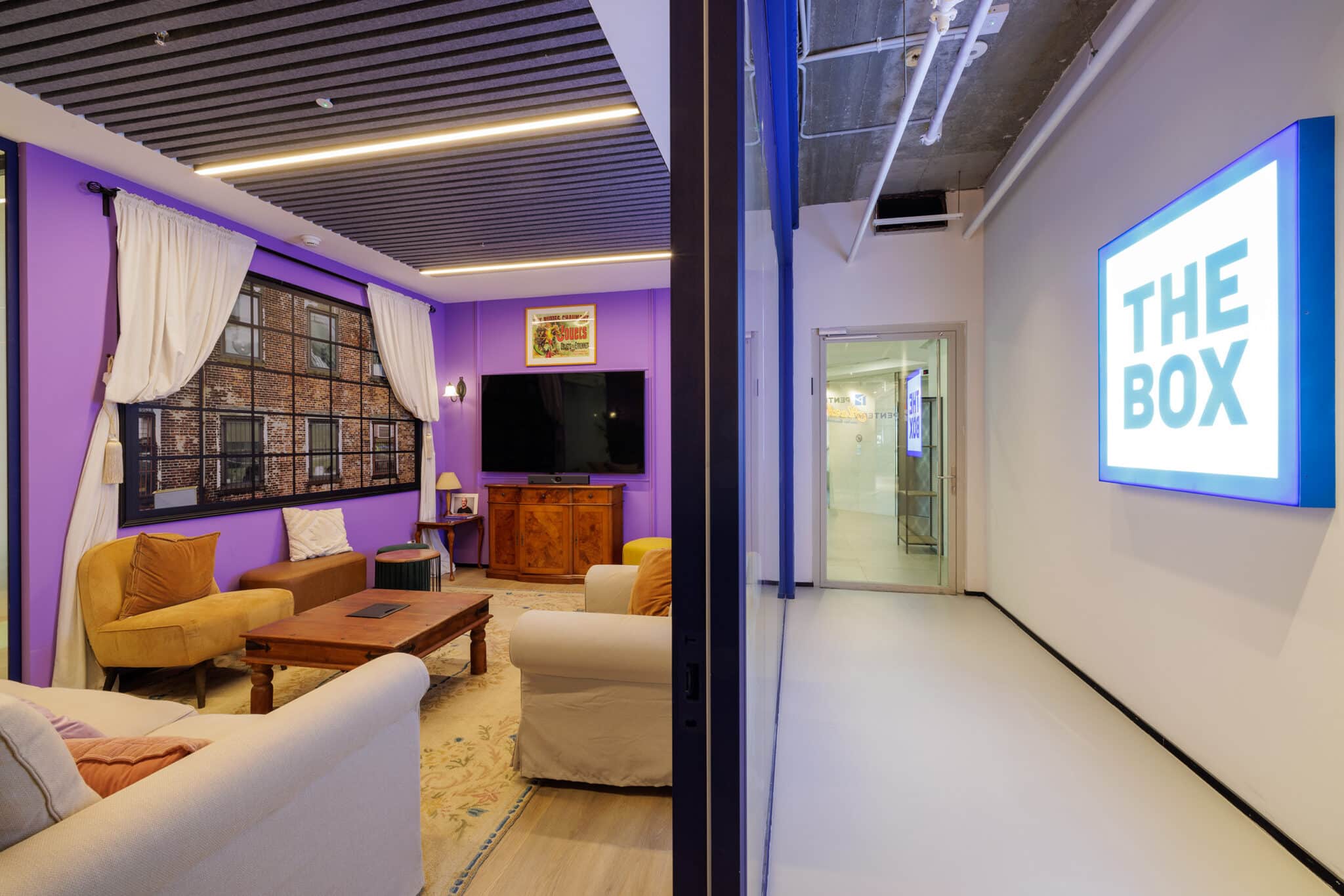 Illuminated THE BOX sign facing a purple themed lounge