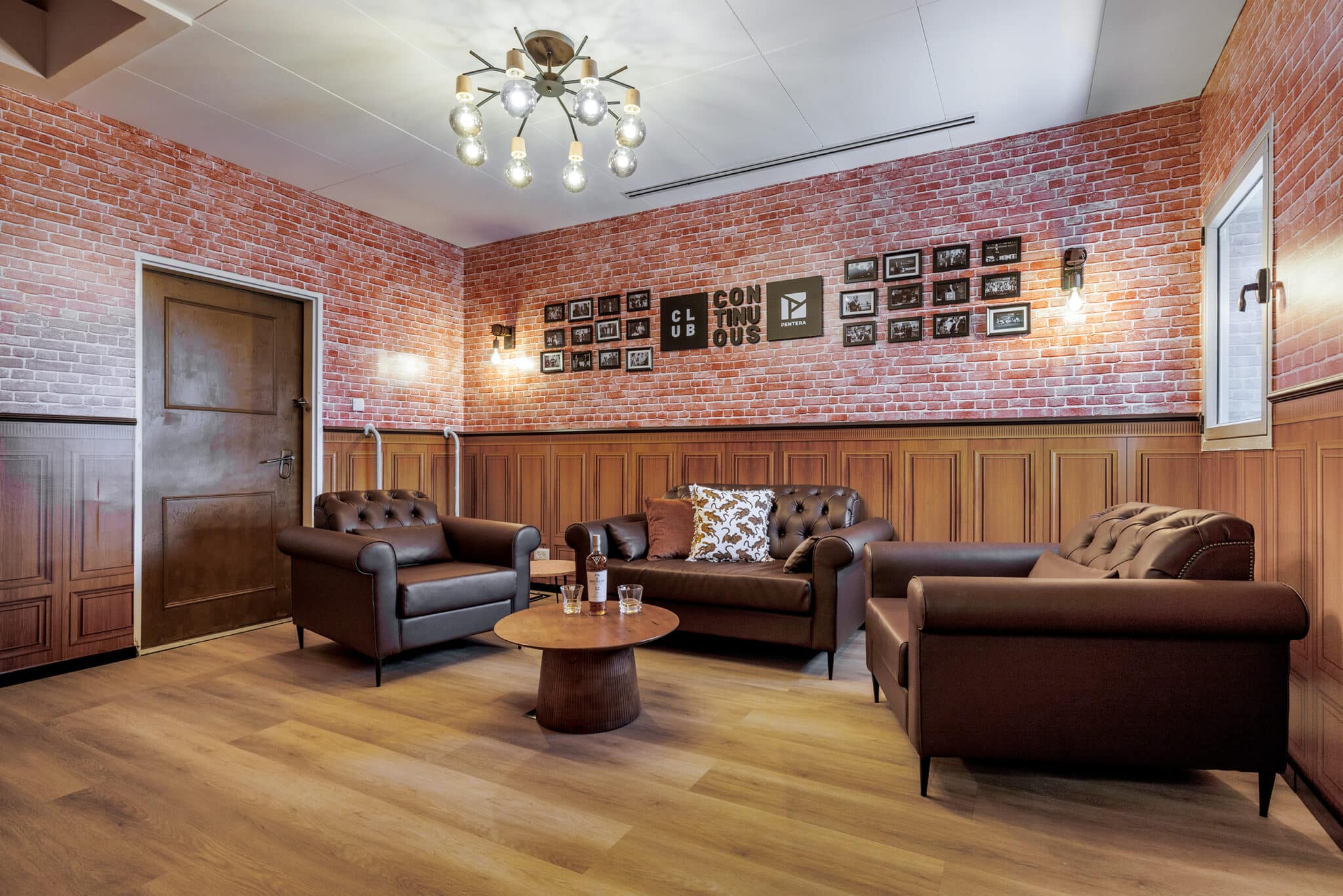 Club lounge with framed photos and a logo sign on brick