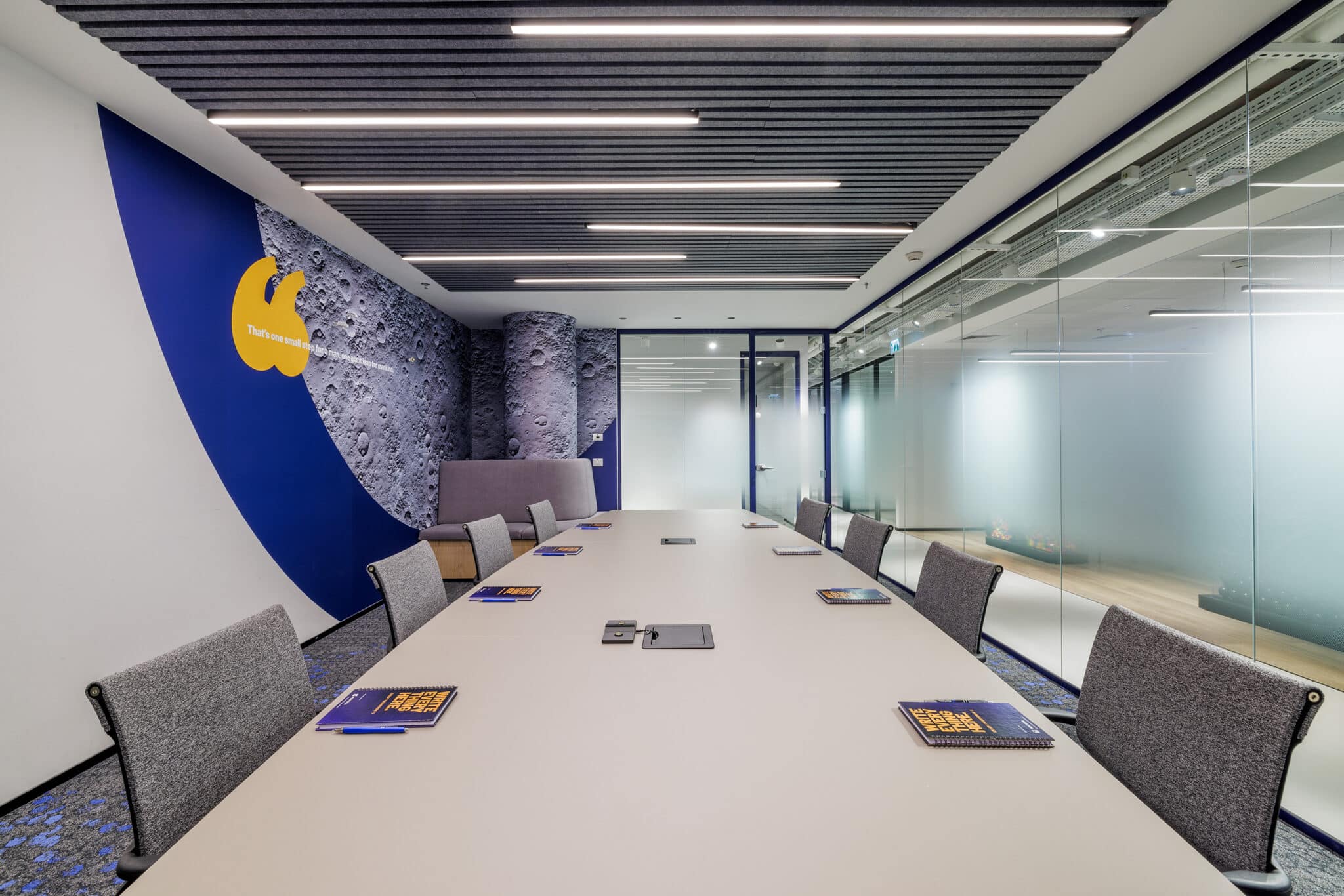 Curved blue wall graphic with a yellow logo in a meeting room