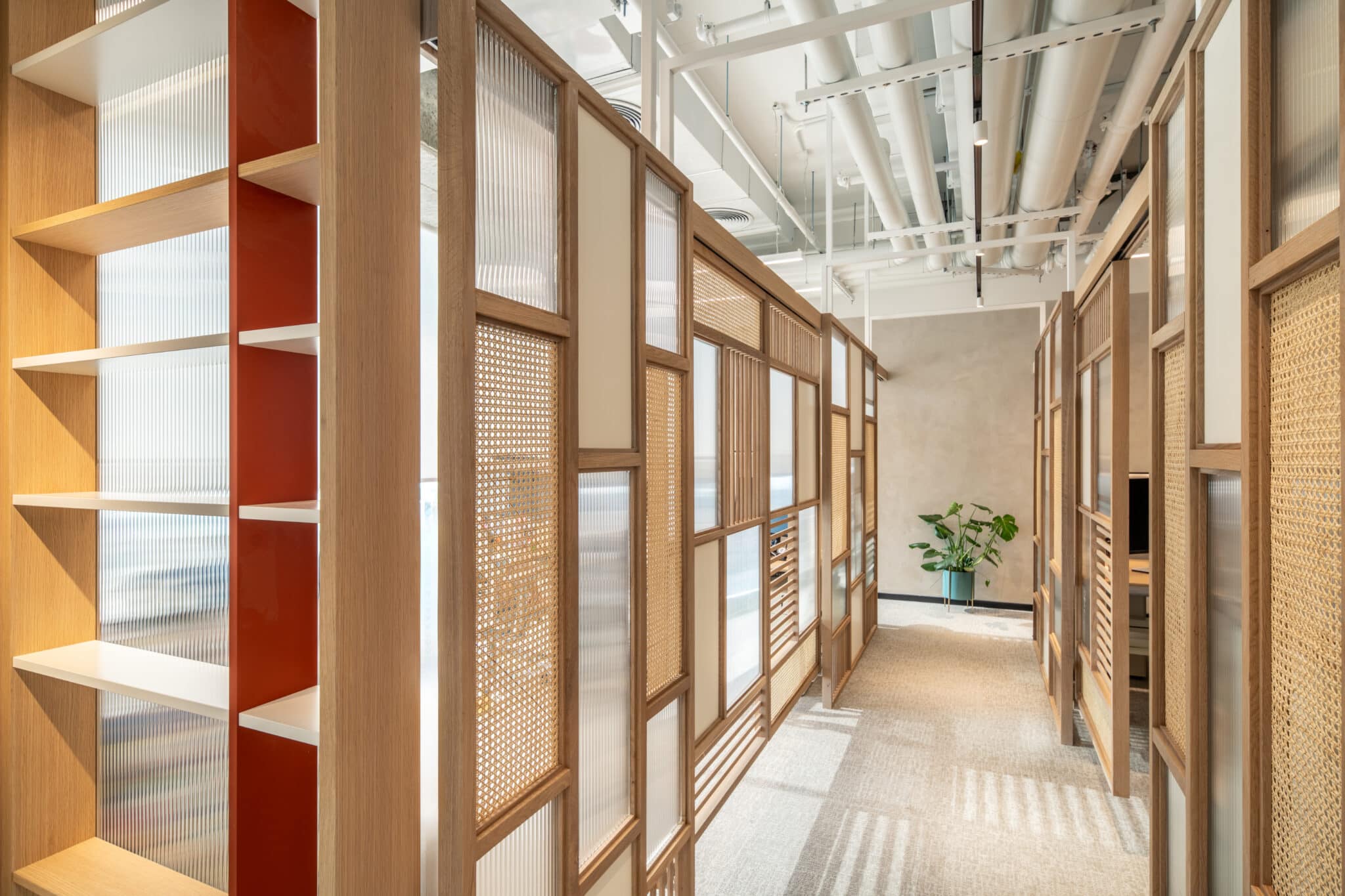 Wood framed screens of fluted glass and rattan lining a corridor
