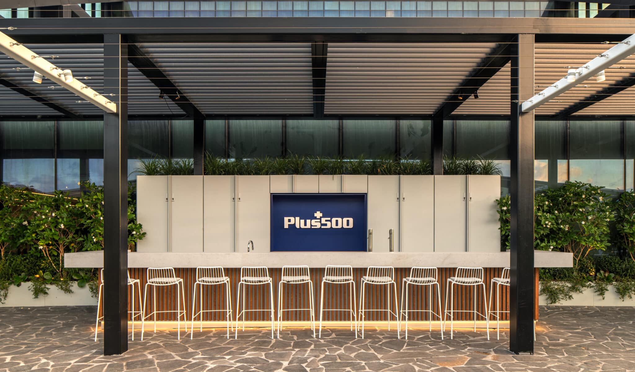 Plus500 logo panel behind the rooftop bar counter
