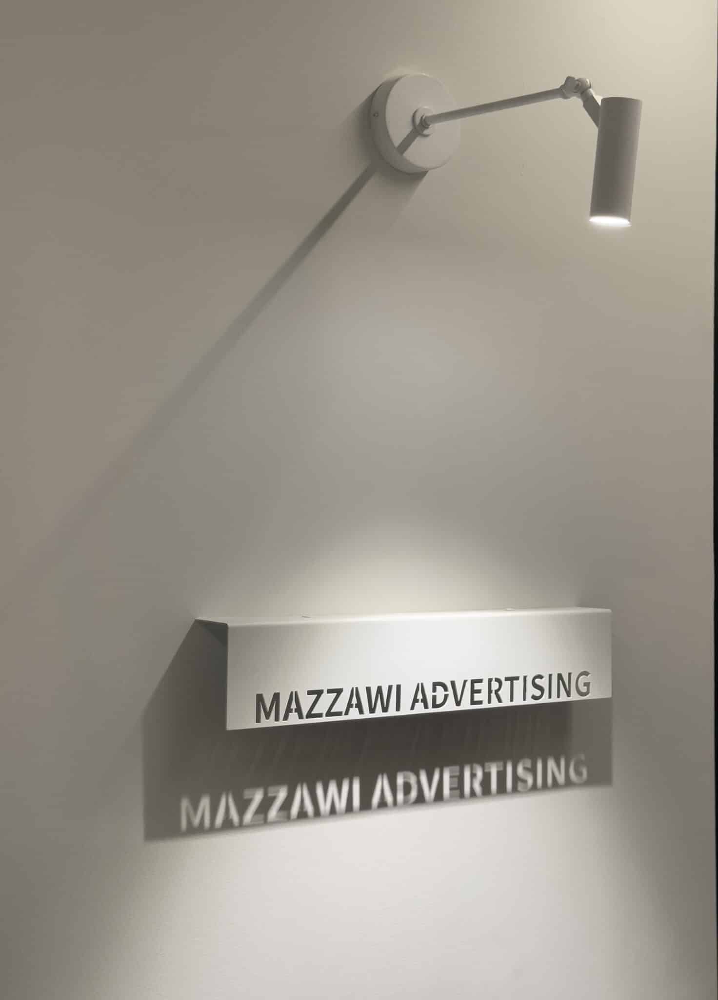 Mazzawi Advertising office sign in cut metal letters under a wall light