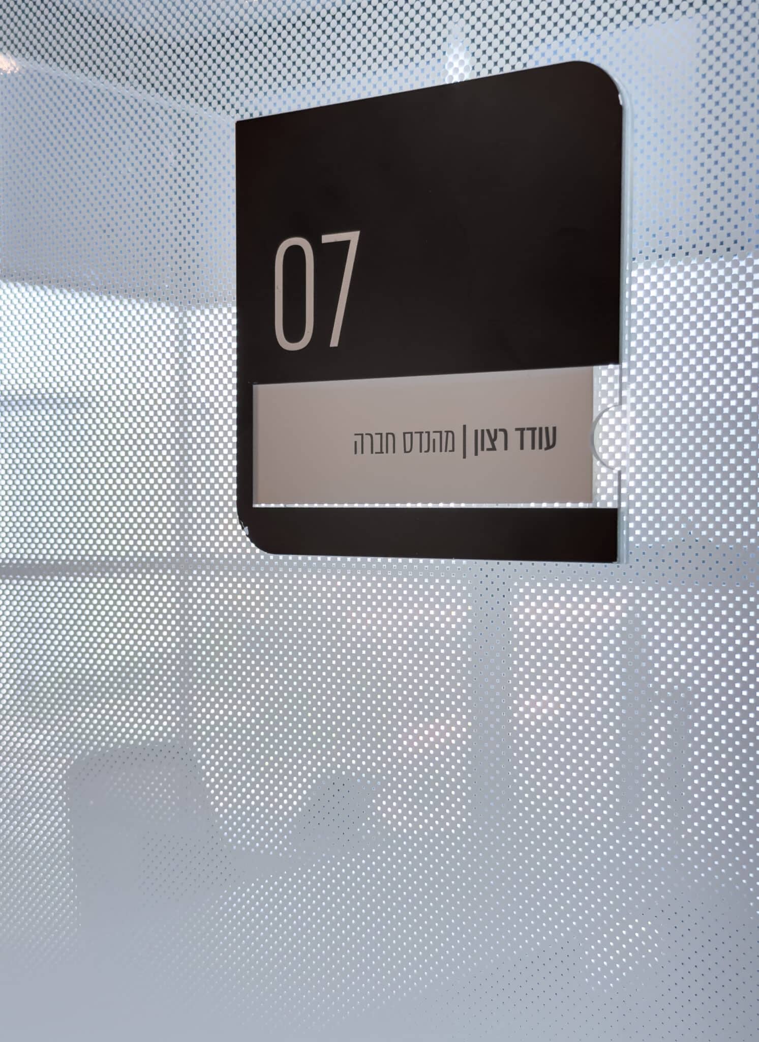 Two-tone room sign with number and name on perforated glass