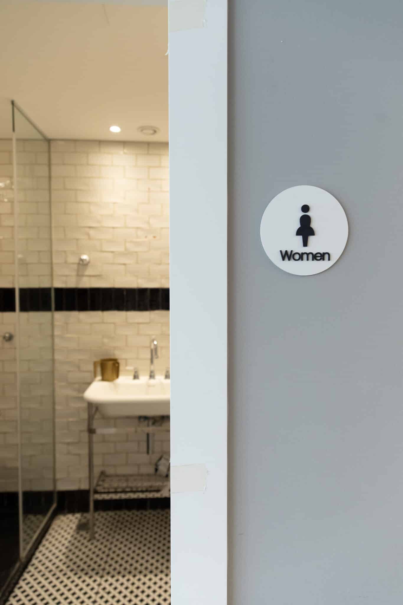 Round Women washroom sign with a pictogram on a wall