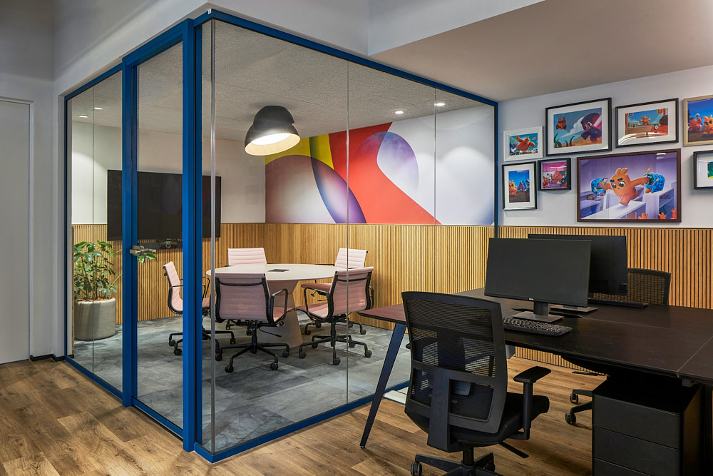 Framed game artwork gallery wall beside a glass meeting room