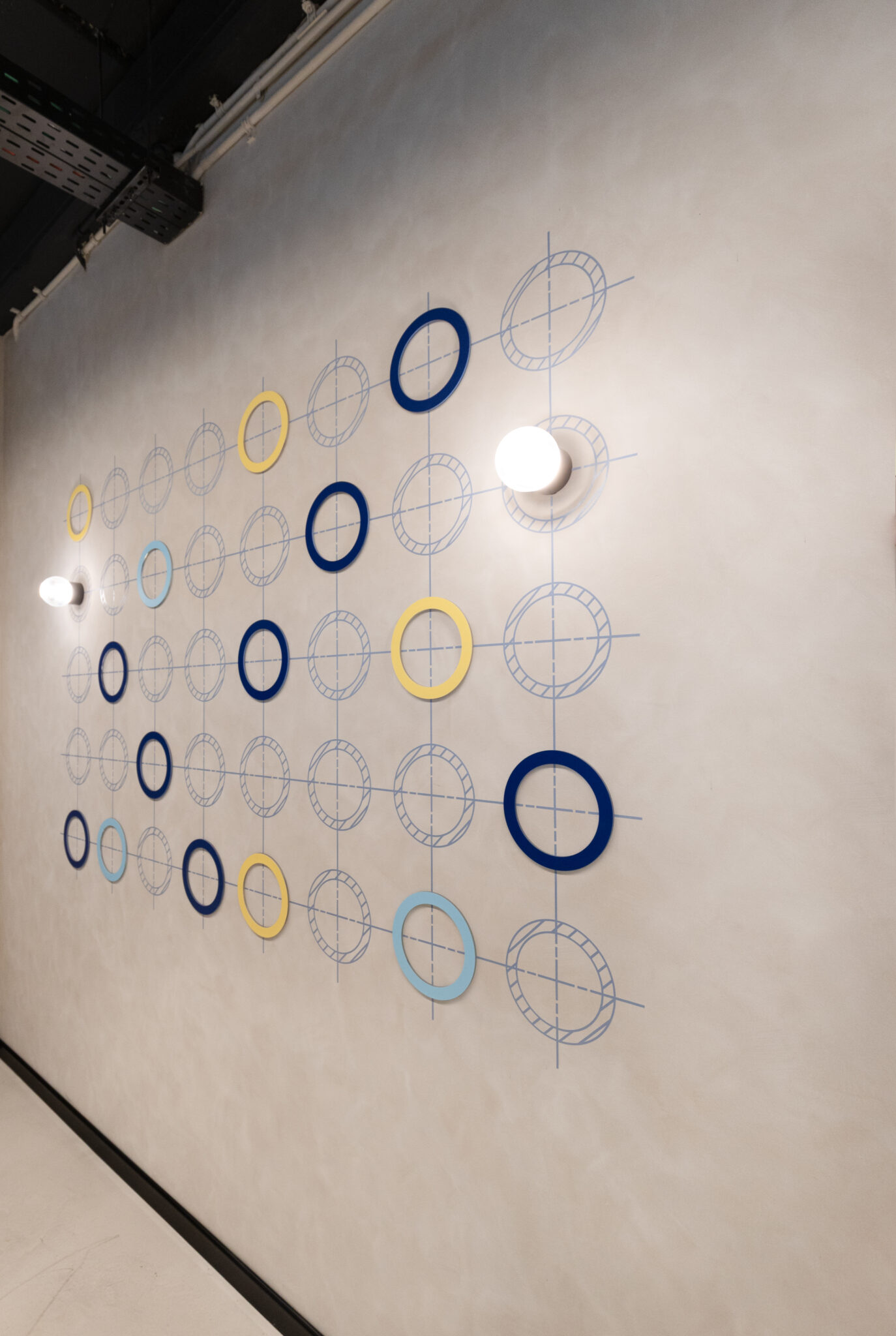 Grid of coloured ring graphics on a concrete wall