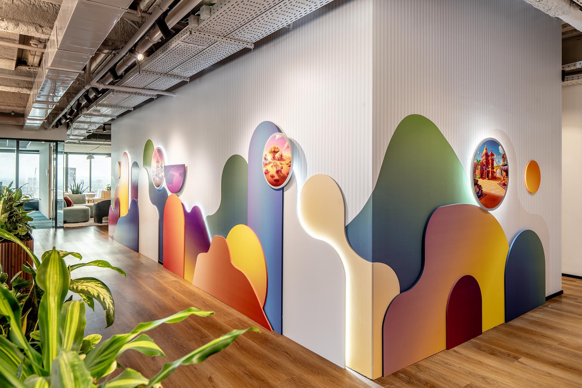 Layered 3D colour shapes and round lit discs on an office wall
